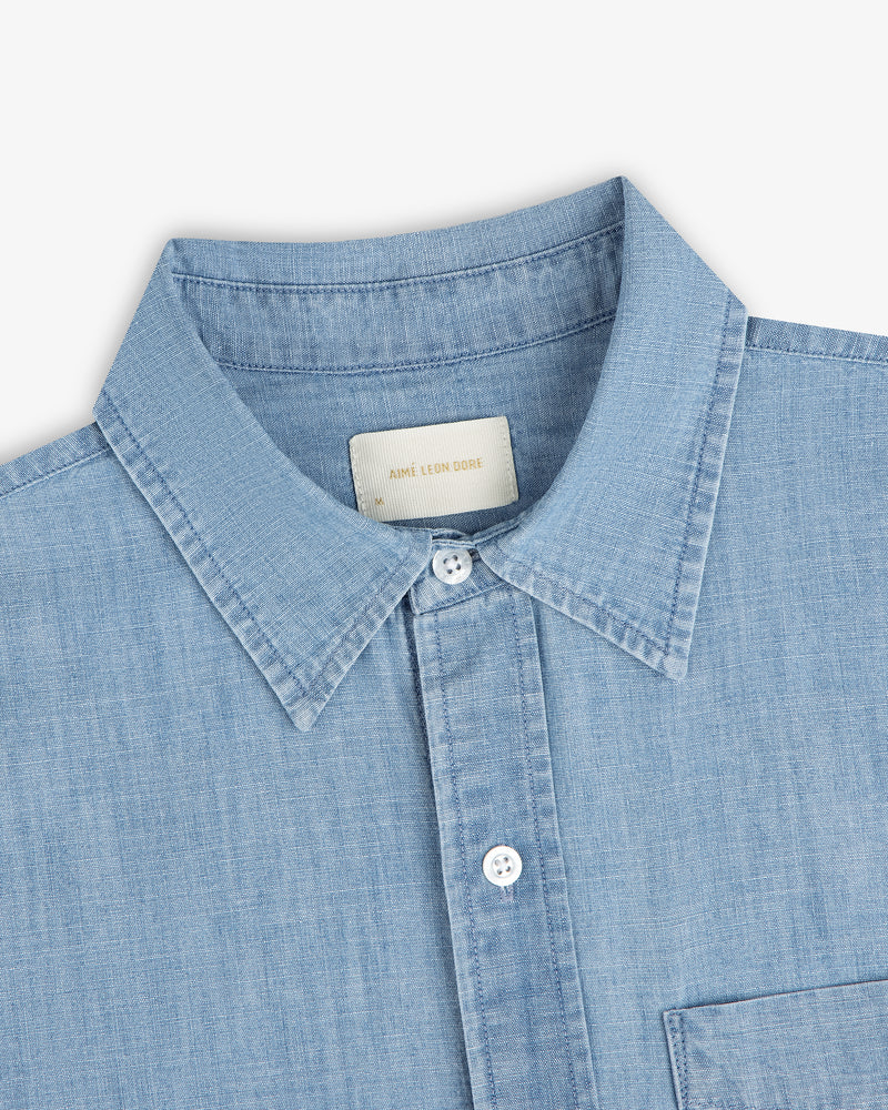 Bayard Chambray Shirt—light blue with a pointed collar, white buttons, and a visible chest pocket.