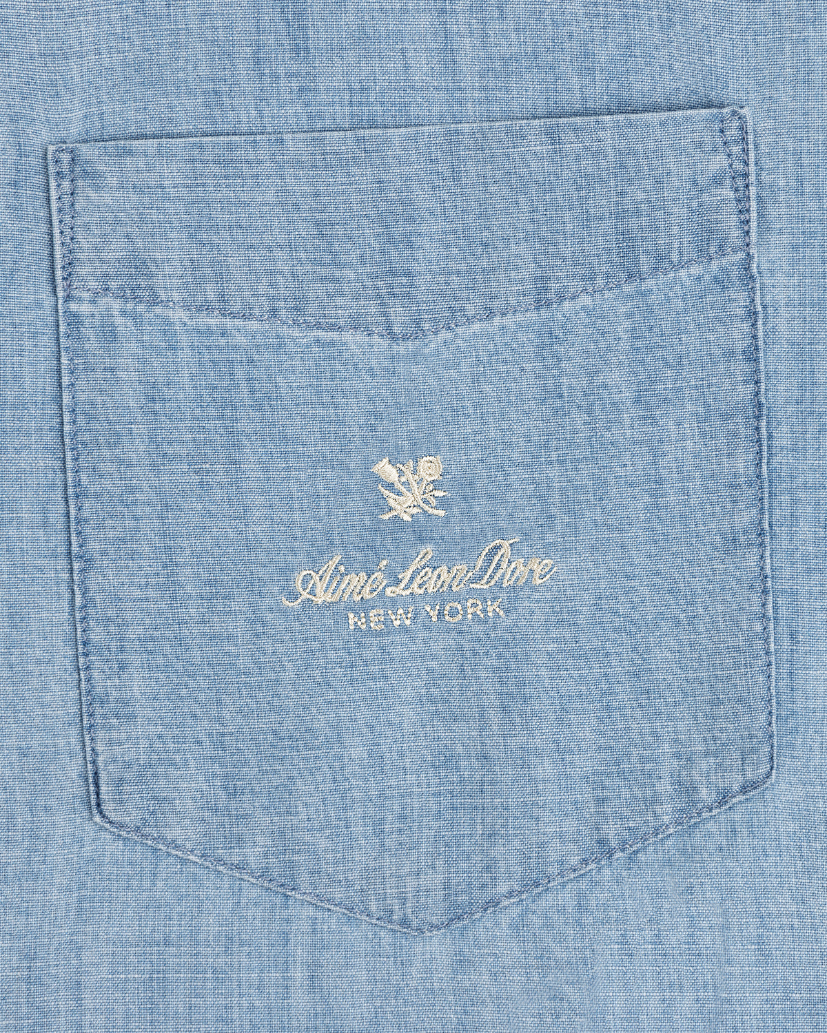 Bayard Chambray Shirt: Light blue pocket with embroidered Aimé Leon Dore New York and small floral logo above.