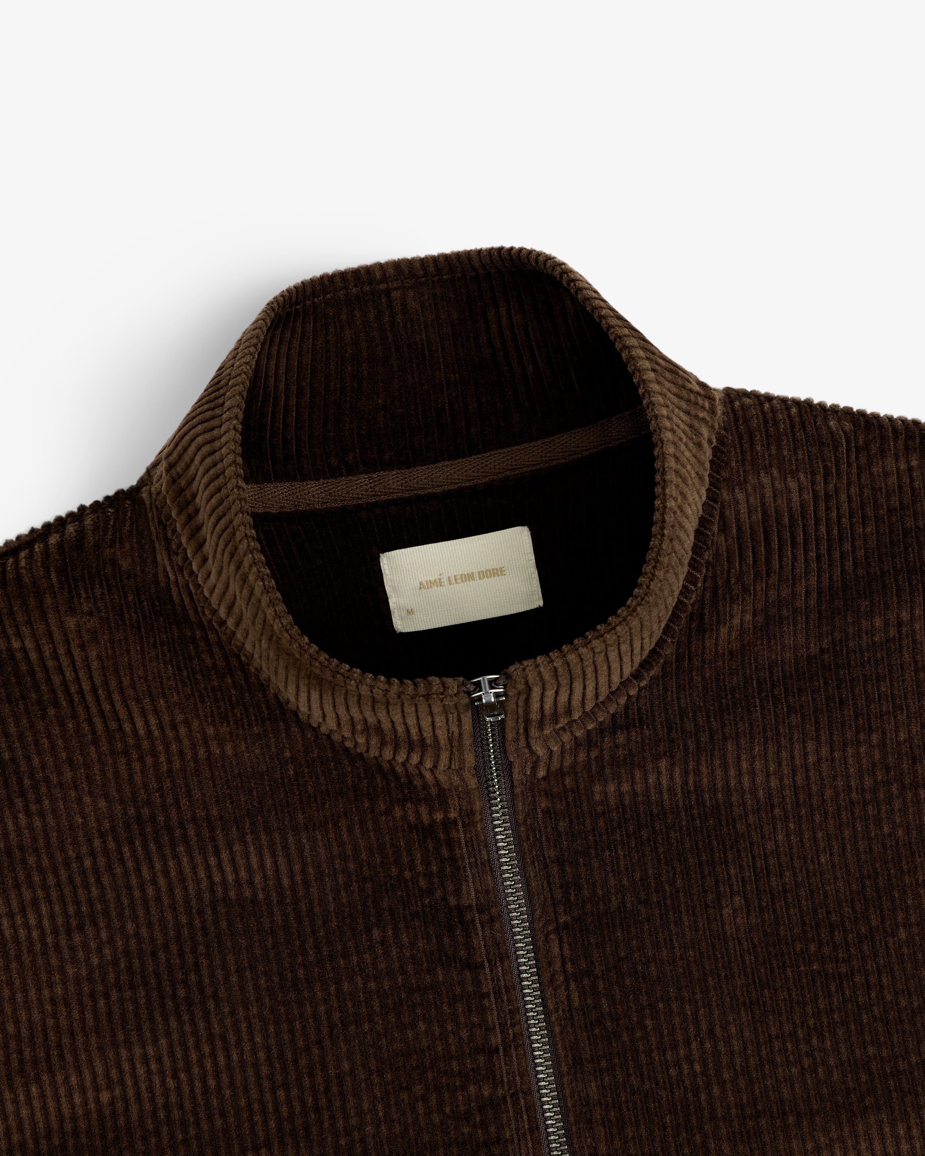 Close-up of a dark brown Quarter Zip Corduroy Shirt featuring a high collar and a branded inner neck label.