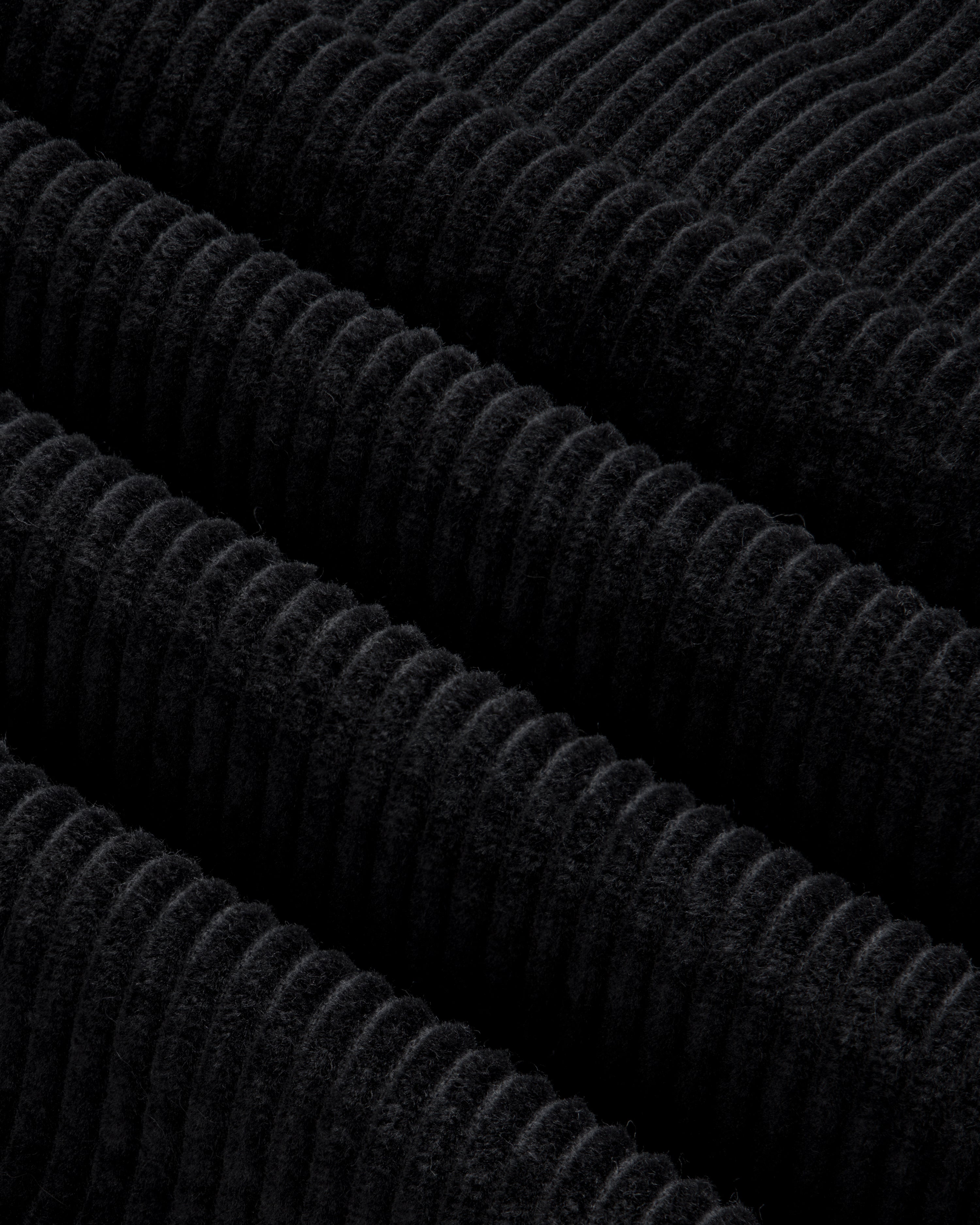 Close-up of black corduroy fabric with thick, diagonal ridges on a Quarter Zip Corduroy Shirt.