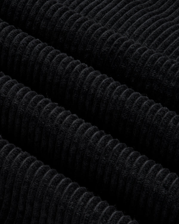 Close-up of black corduroy fabric with thick, diagonal ridges on a Quarter Zip Corduroy Shirt.