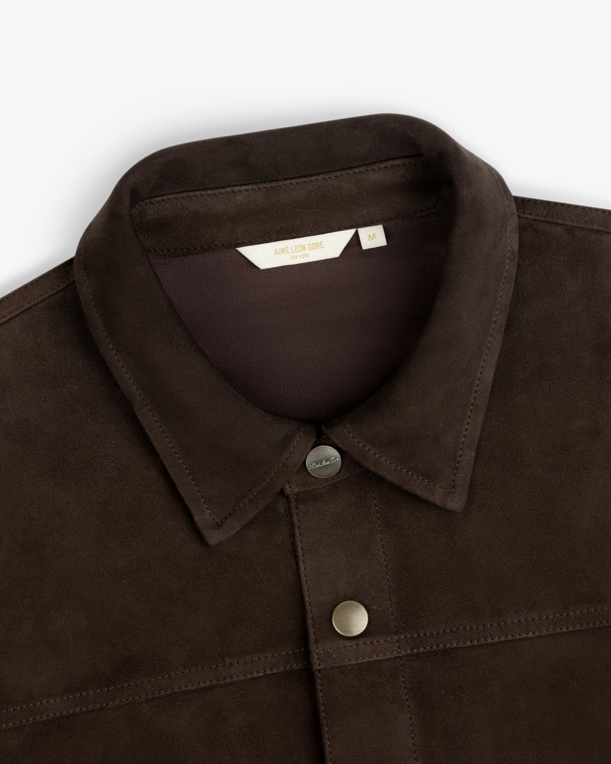 Close-up of a dark brown Suede Overshirt with a classic collar and metal snap buttons.