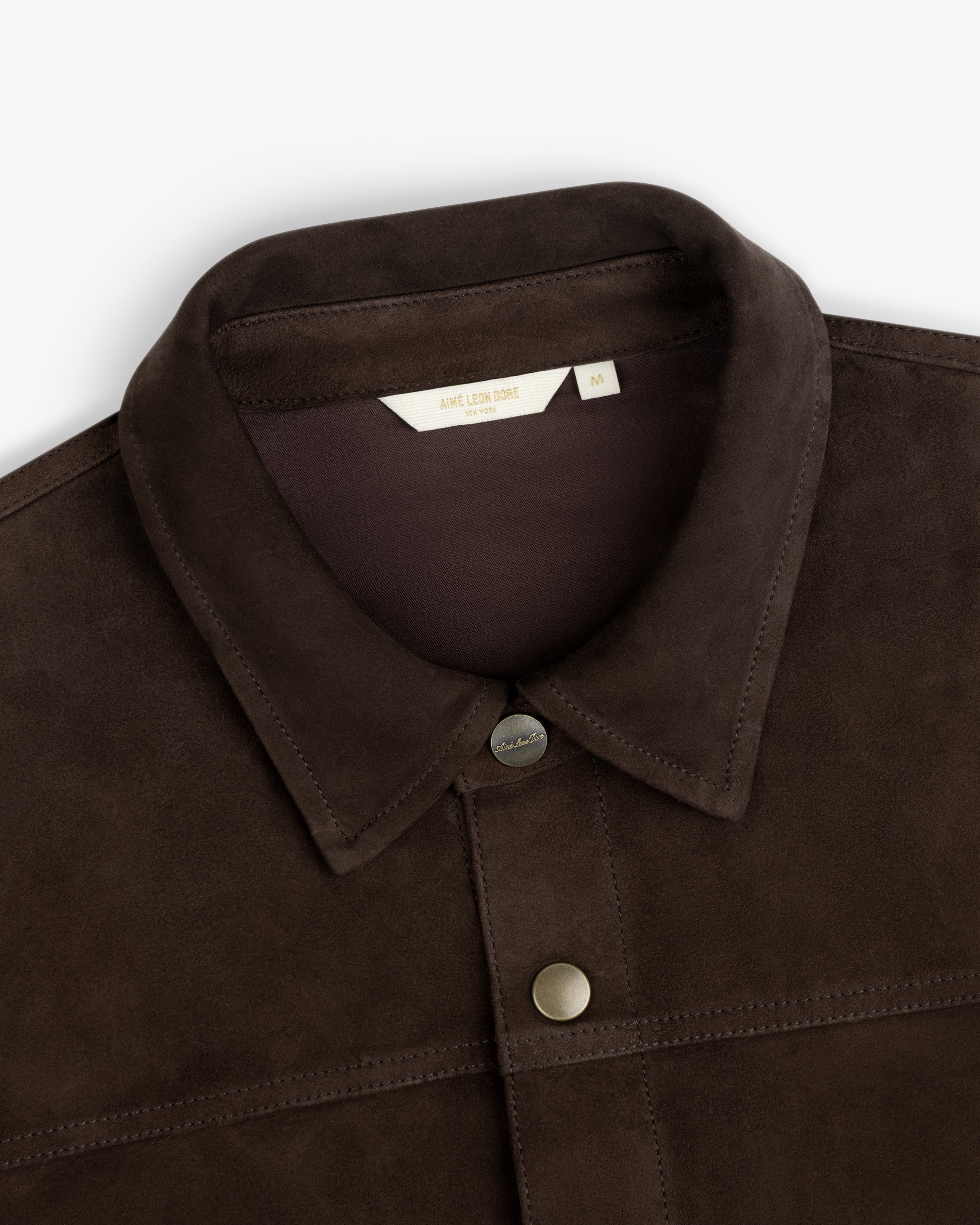 Close-up of a dark brown Suede Overshirt with a classic collar and metal snap buttons.