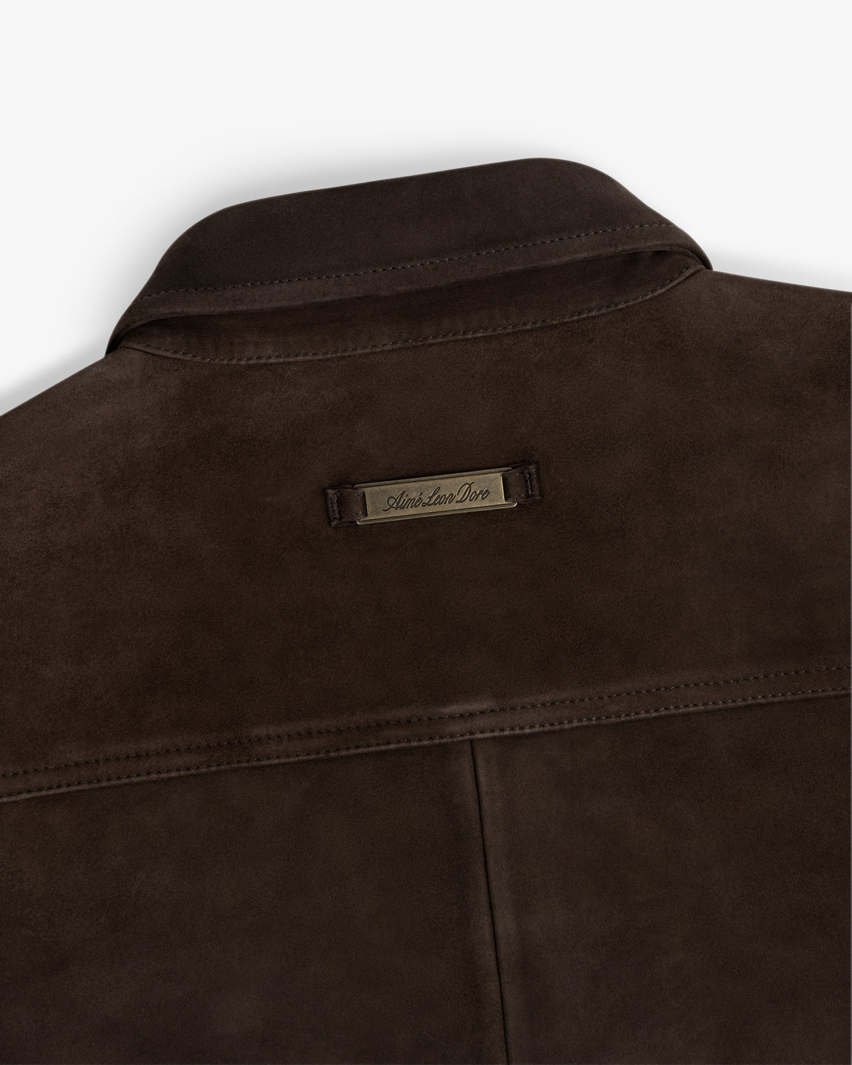 Dark brown Suede Overshirt collar featuring a metal brand tag at the nape.