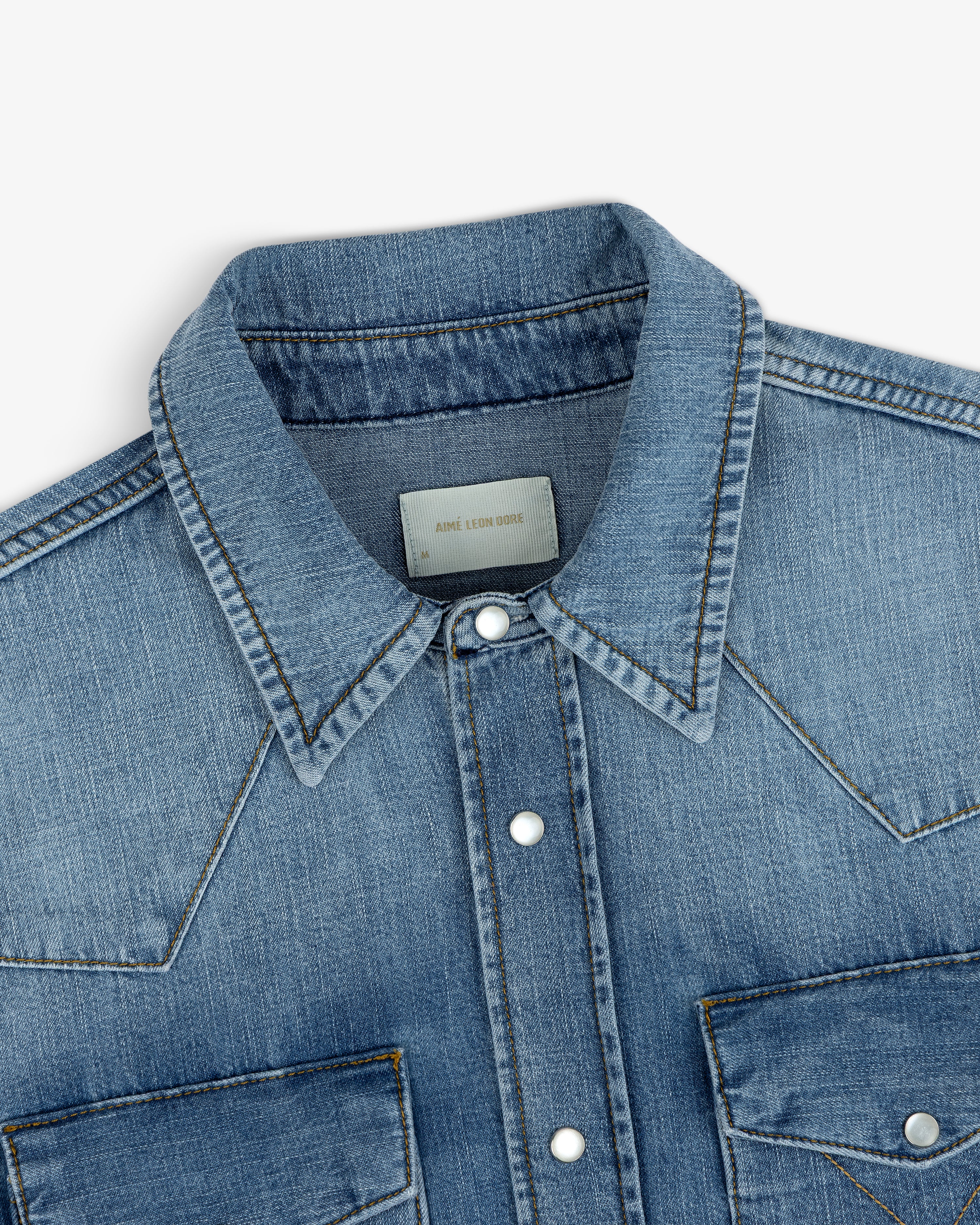 Close-up of a blue Denim Western Shirt featuring silver snap buttons and front chest pockets.