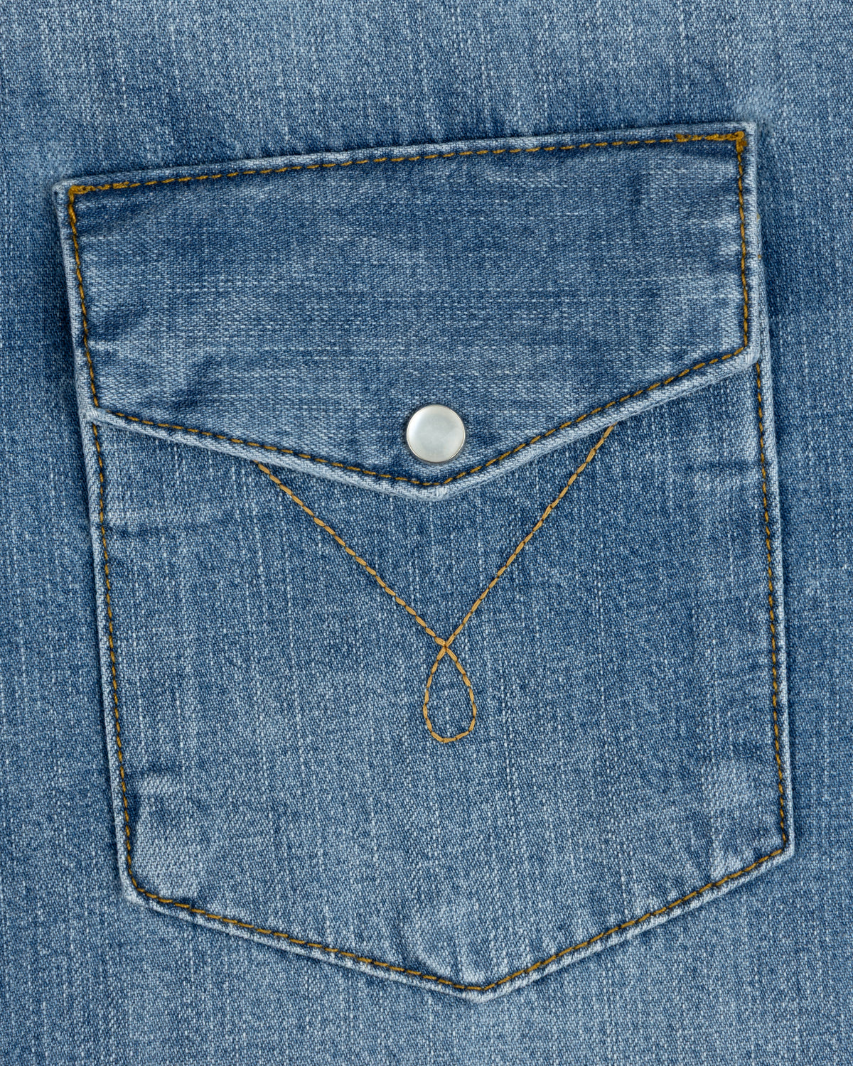 Blue denim chest pocket on a Denim Western Shirt with a pointed flap, silver snap button, and decorative gold stitching.