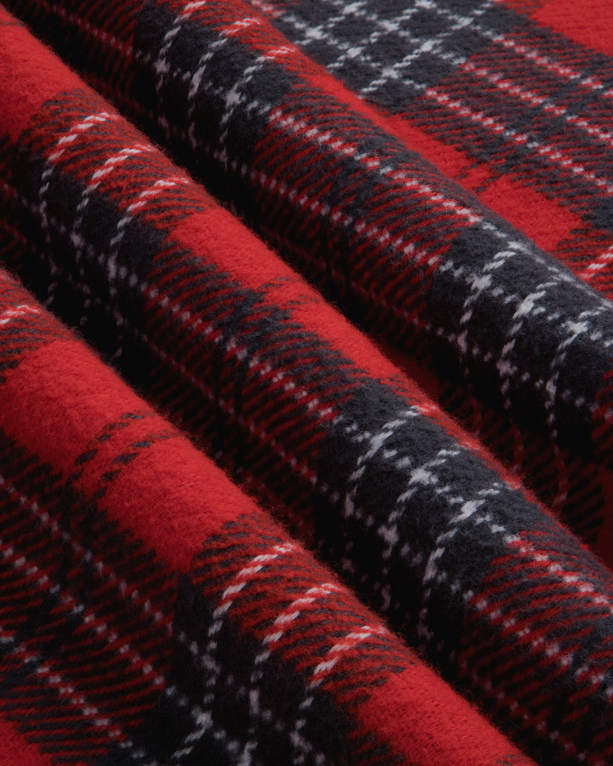 Close-up of a Yarn Dyed Plaid Overshirt featuring a red, black, and white plaid pattern with deep folds.