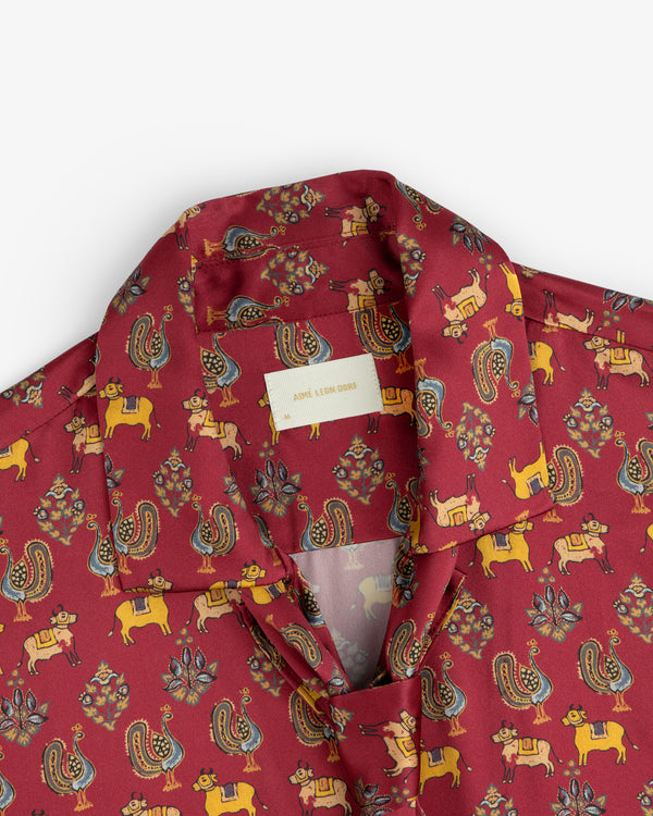 Archival Print Silk Tie Neck Blouse in red with a collar and a repeating print of stylized animals and floral motifs.