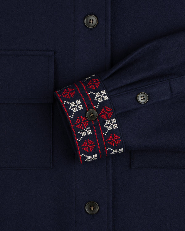Mani Embroidered Wool Jacket in navy with red and white geometric cross-stitch cuffs and dark buttons.