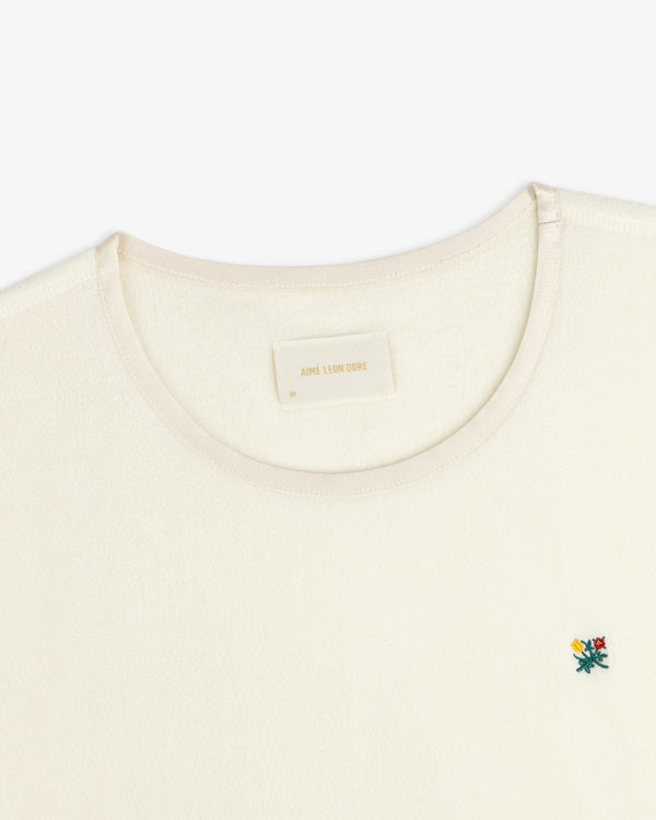 Cream-colored Crest Long-Sleeve Fleece Tee with an embroidered floral icon and interior neck label.
