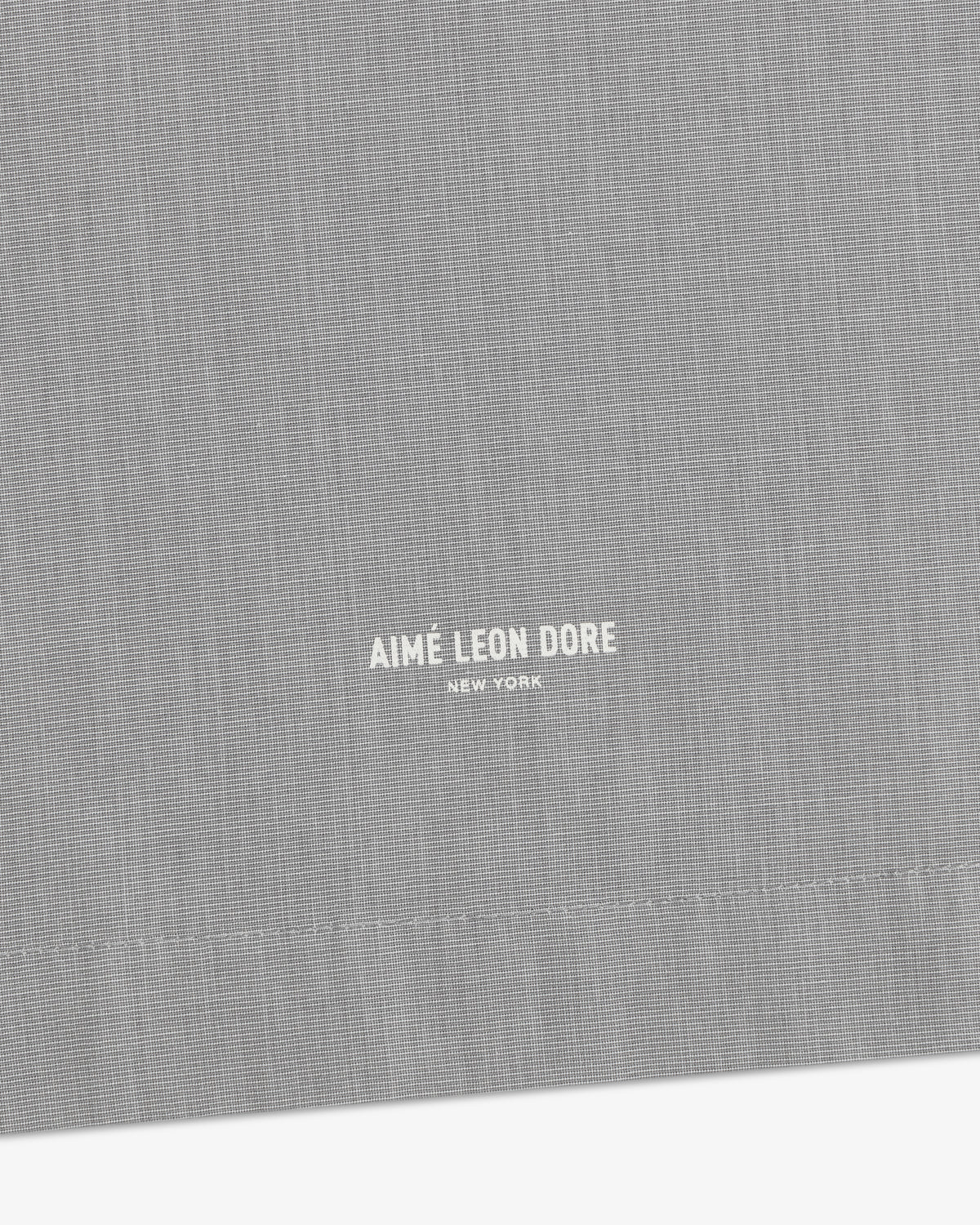 Close-up of gray Poplin Casual Shirt featuring small white Aimé Leon Dore New York text near the bottom center.