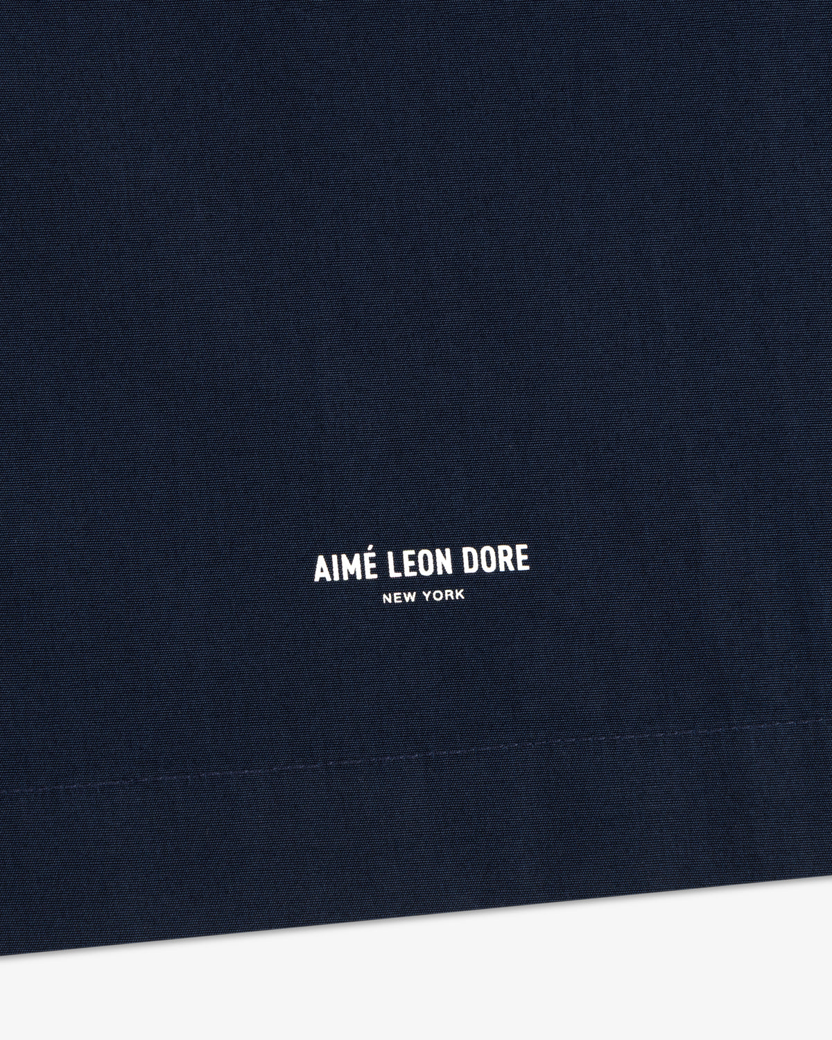 Close-up of navy Poplin Casual Shirt fabric with small white AIMÉ LEON DORE NEW YORK text centered at the bottom.