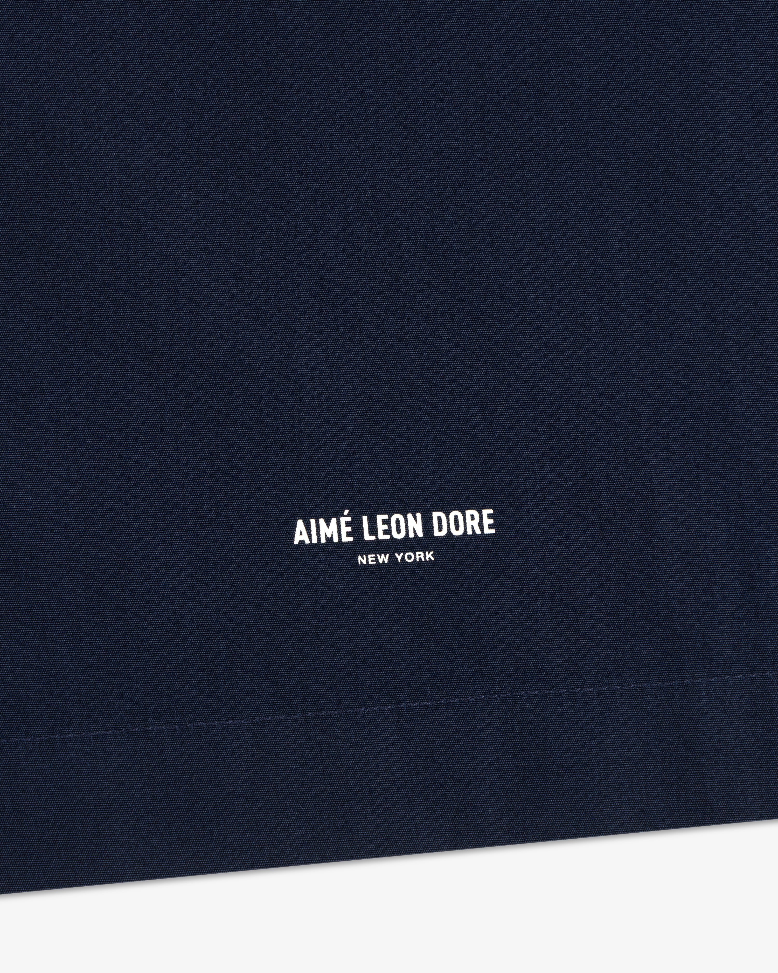 Close-up of navy Poplin Casual Shirt fabric with small white AIMÉ LEON DORE NEW YORK text centered at the bottom.