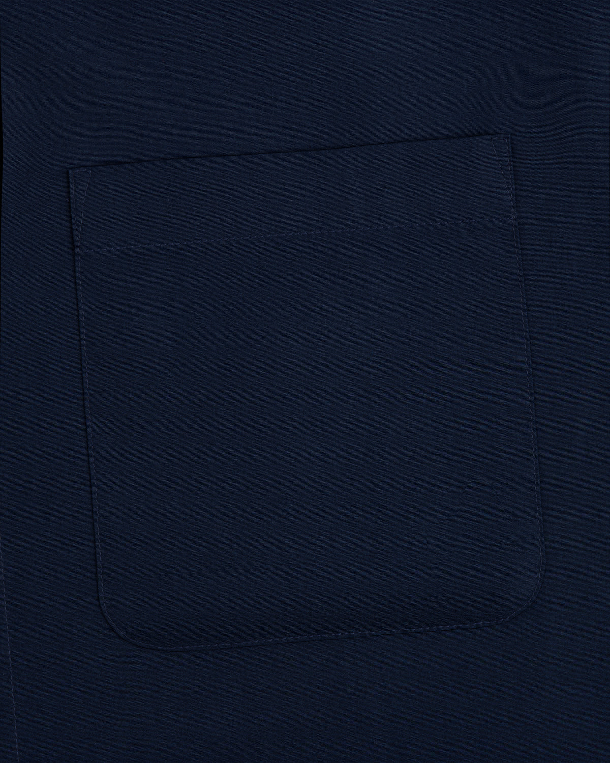 A close-up of a square, navy pocket sewn onto matching Poplin Casual Shirt fabric.