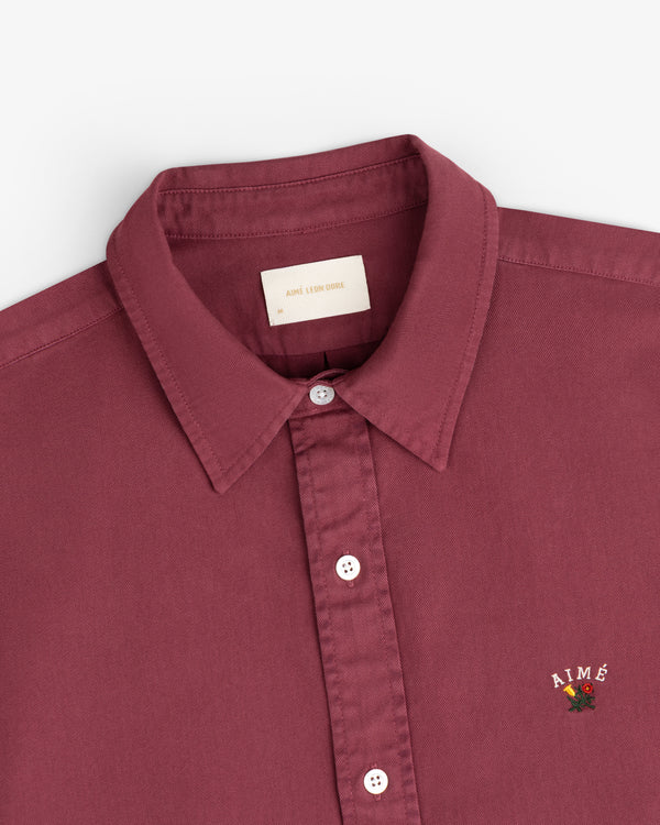Garment Dyed Leon Overshirt in maroon with AIMÉ and floral chest embroidery, laid flat on a white background.