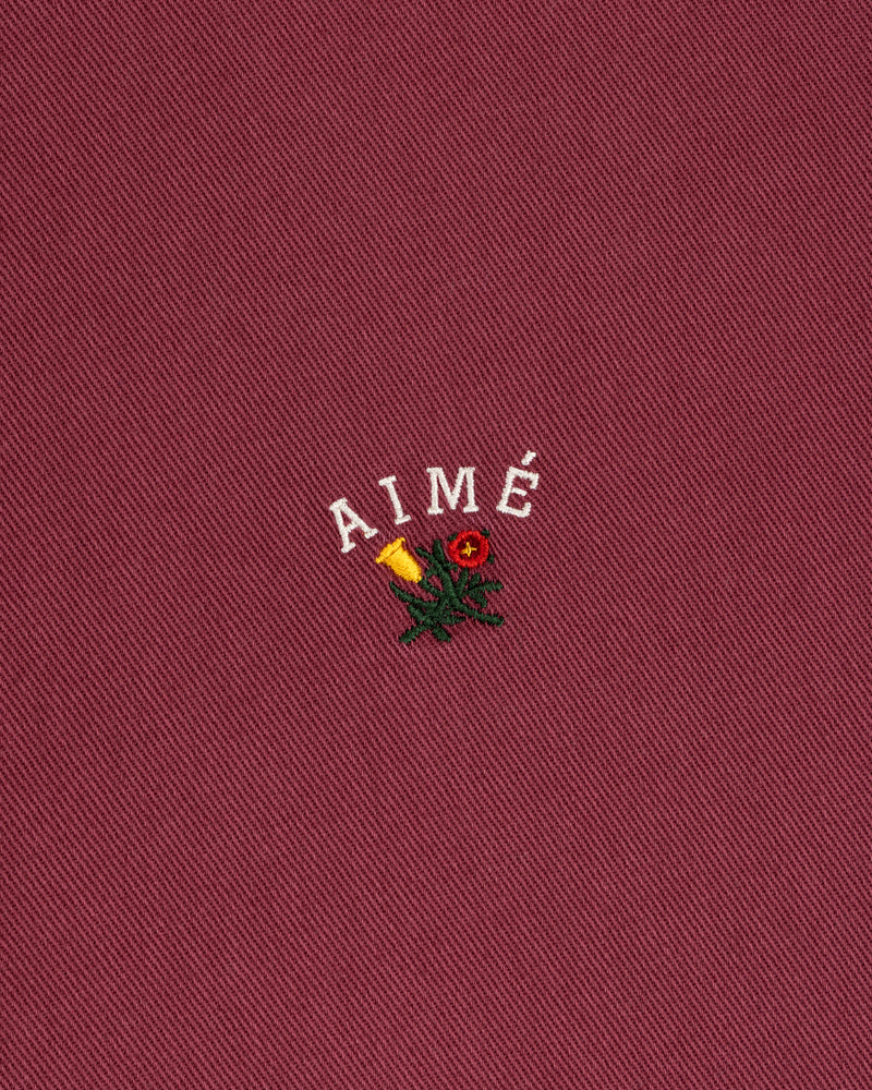 Garment Dyed Leon Overshirt: red with white AIMÉ text, yellow rose, and green leaves embroidery.