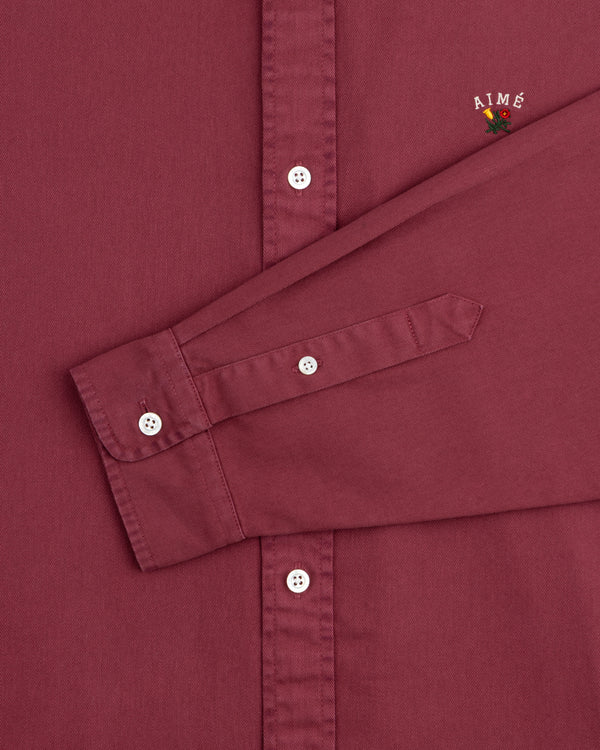 Garment Dyed Leon Overshirt in maroon with white buttons, visible sleeve, and AIMÉ flower embroidery.