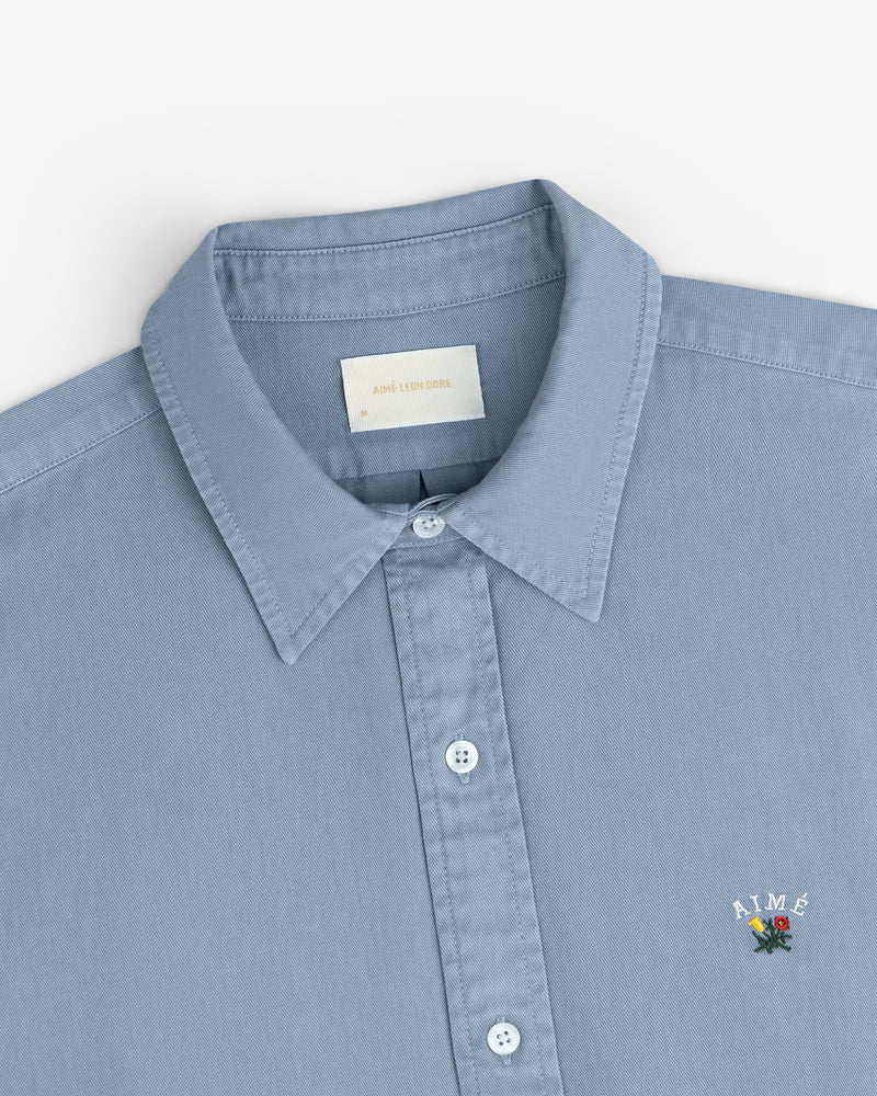 Light blue Garment Dyed Leon Overshirt with collar and ‘AIMÉ.’ motif embroidered above the left hem.