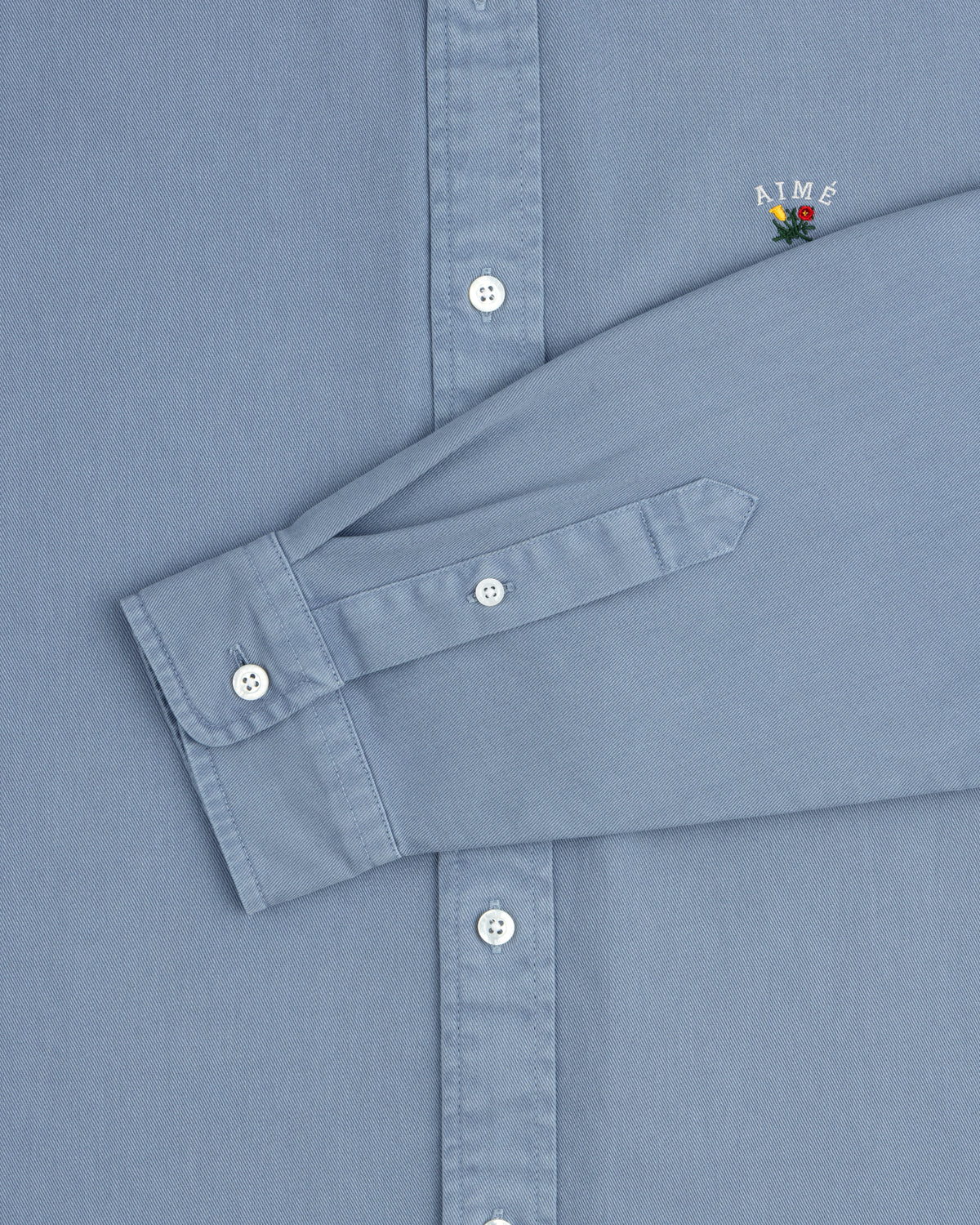 Garment Dyed Leon Overshirt: light blue, white buttons, small AIMÉ embroidery above the cuff.