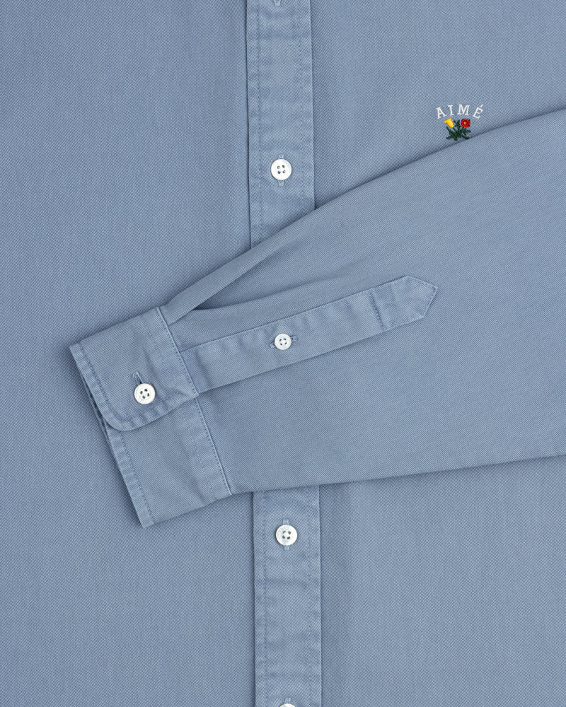 Garment Dyed Leon Overshirt: light blue, white buttons, small AIMÉ embroidery above the cuff.