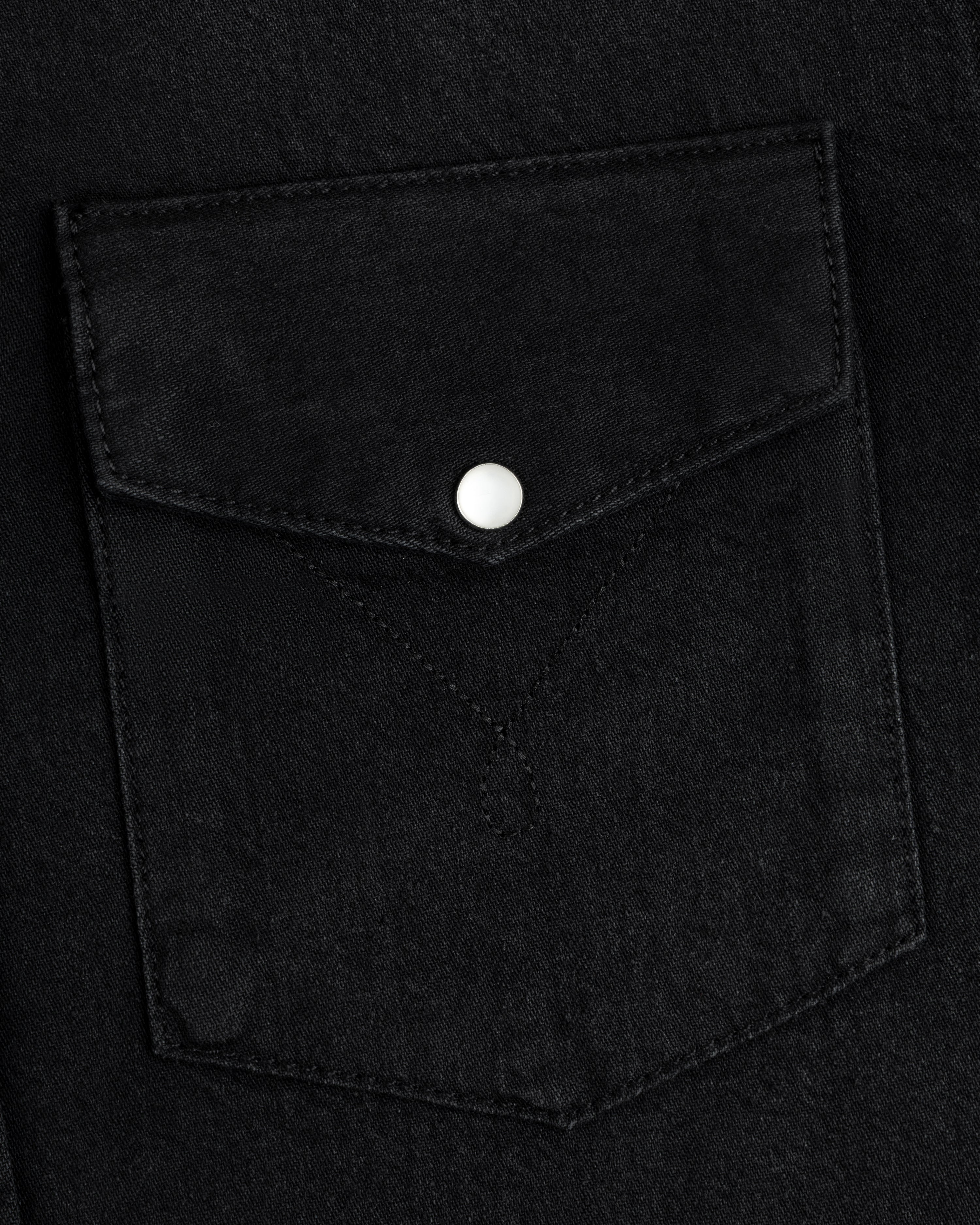 Denim Western Shirt pocket in black denim with a pointed flap and a single silver snap button.