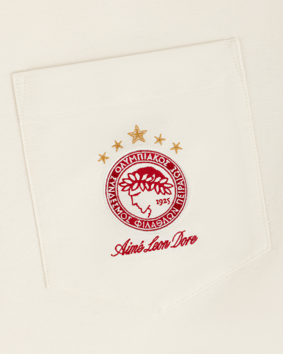 An ALD / Olympiacos F.C. Logo Oxford Shirt pocket with an embroidered crest featuring a laurel-crowned profile and stars.