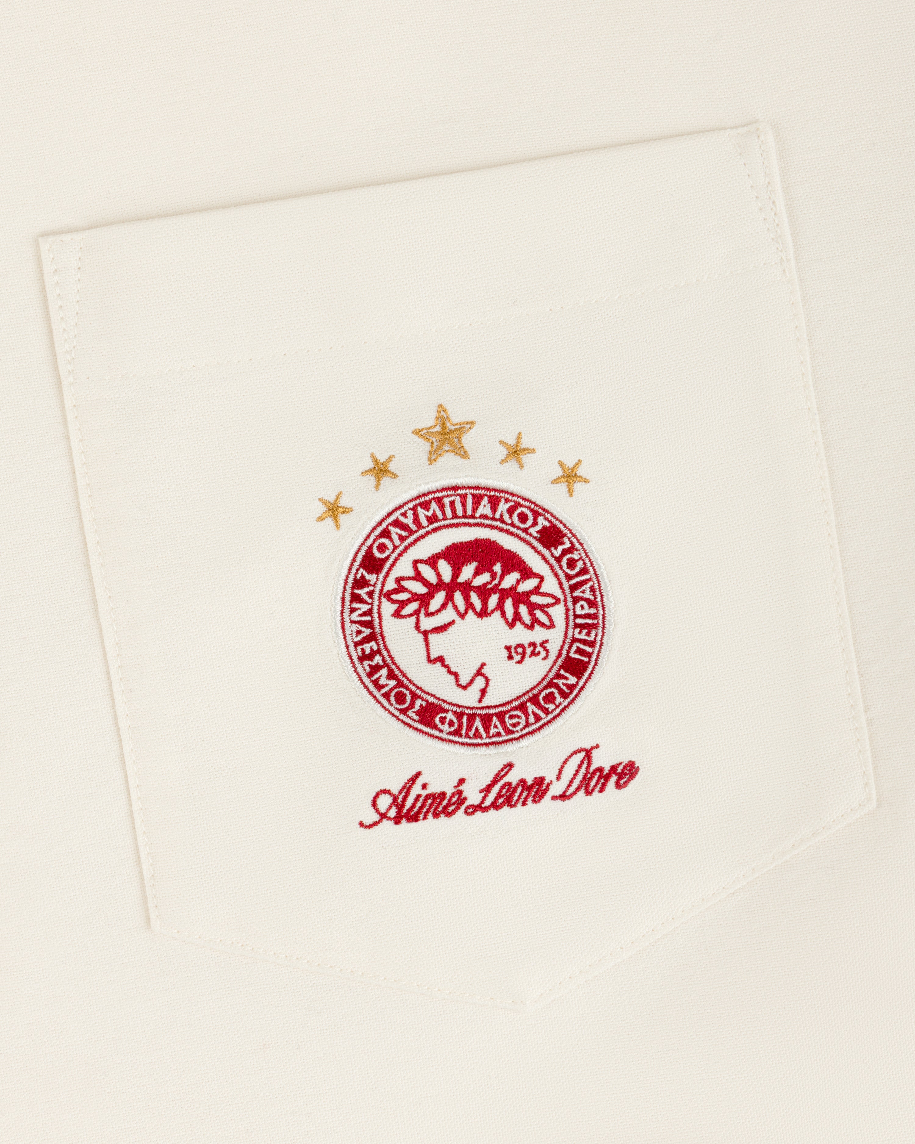 An ALD / Olympiacos F.C. Logo Oxford Shirt pocket with an embroidered crest featuring a laurel-crowned profile and stars.