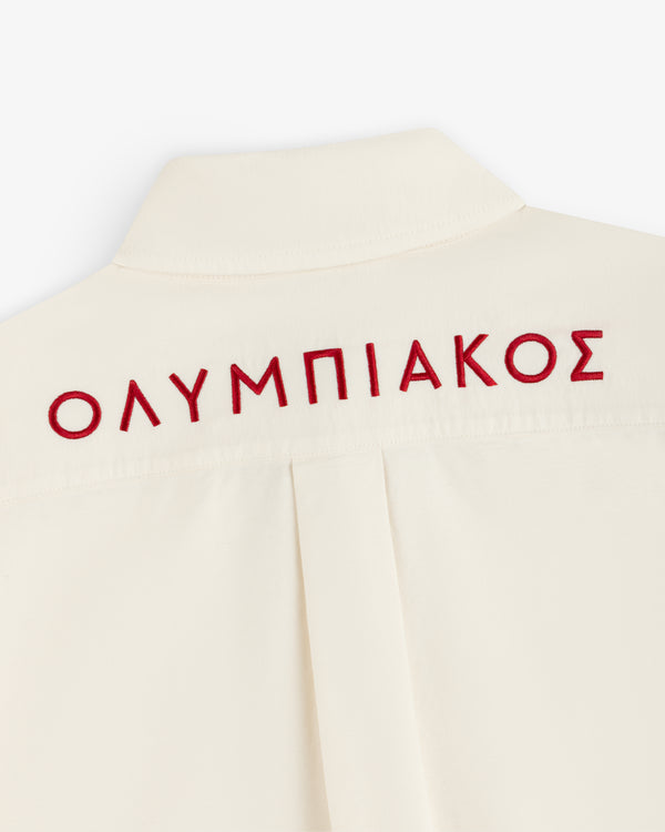 Cream-colored ALD / Olympiacos F.C. Logo Oxford Shirt with the Greek word ΟΛΥΜΠΙΑΚΟΣ embroidered in red on the back.