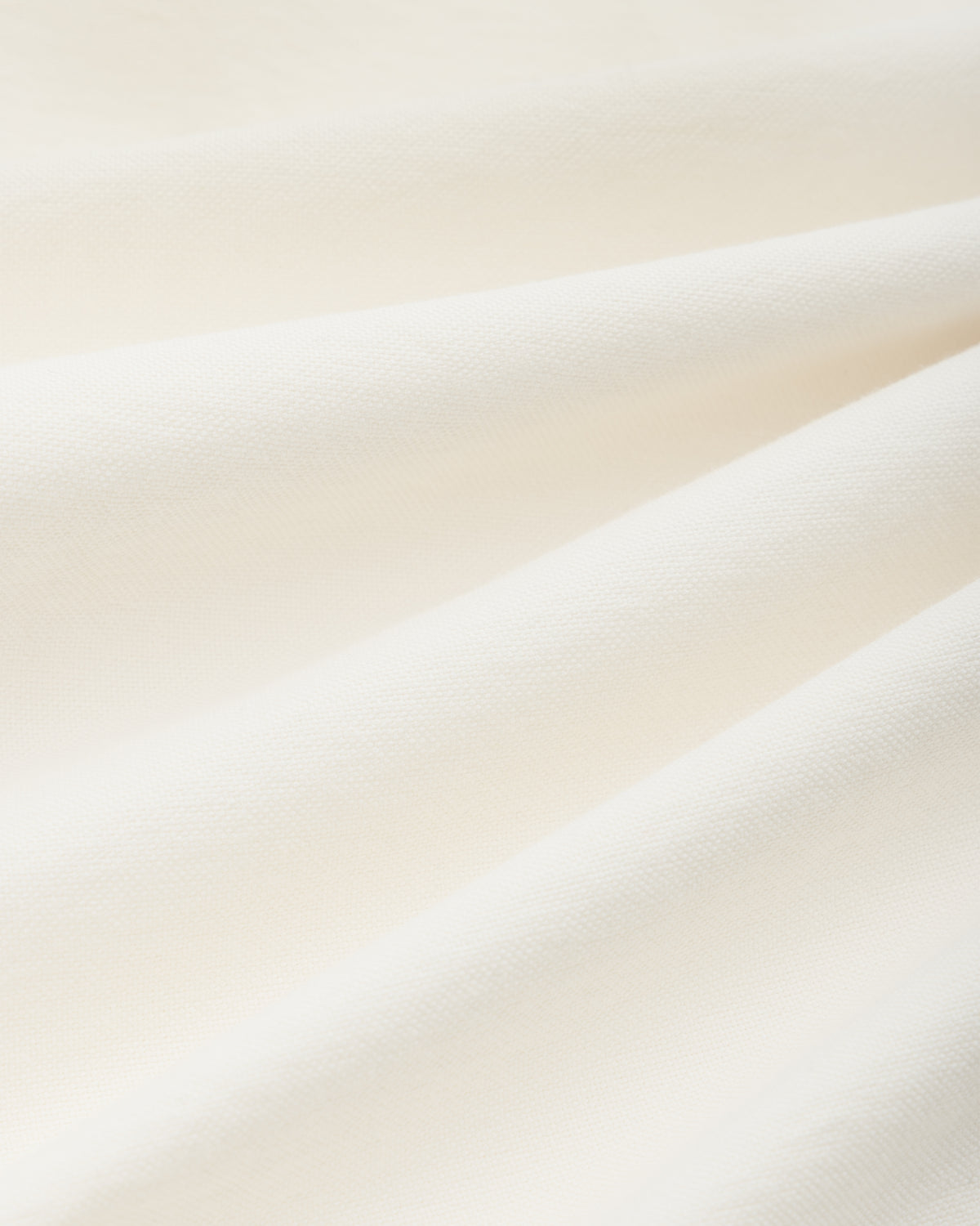 Close-up of off-white woven fabric with soft folds on an ALD / Olympiacos F.C. Logo Oxford Shirt.