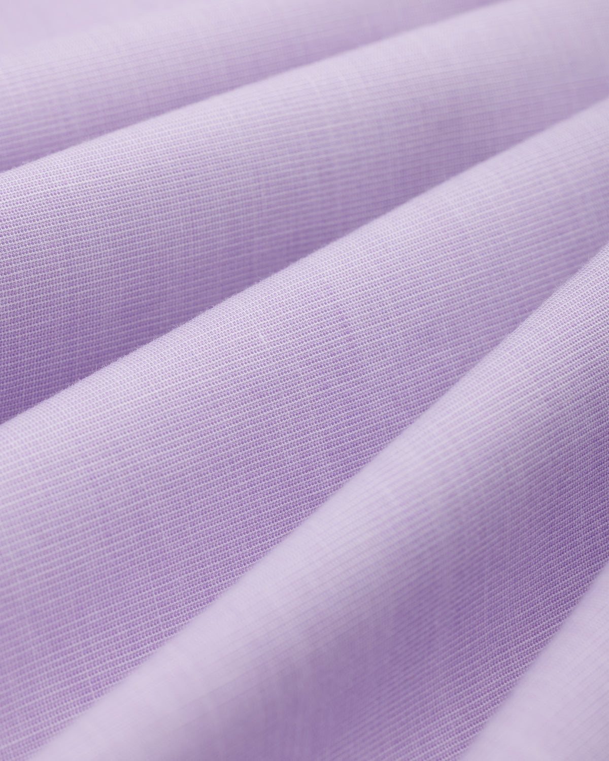 Close-up of light purple Button Down Poplin Shirt fabric with diagonal folds.