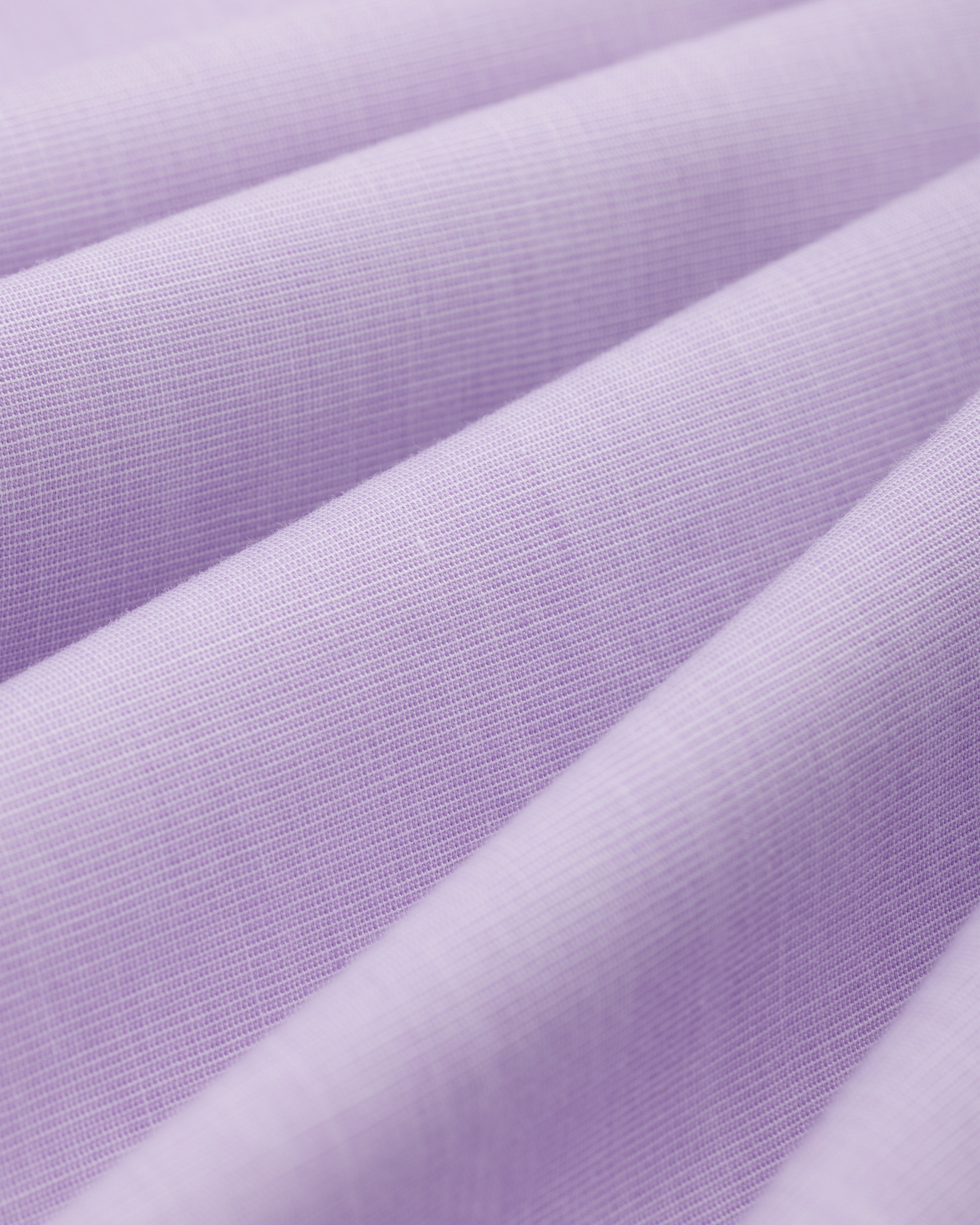 Close-up of light purple Button Down Poplin Shirt fabric with diagonal folds.