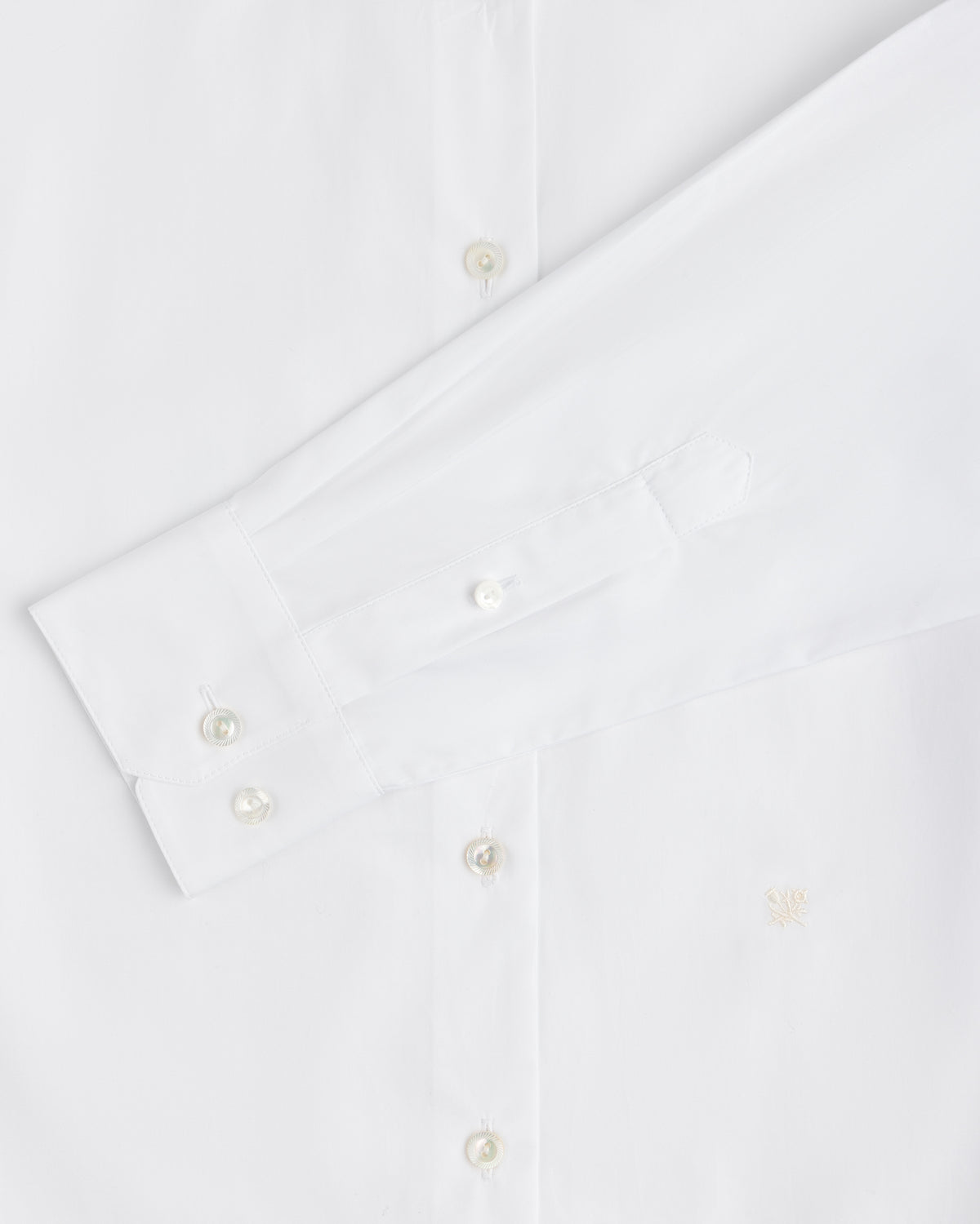 Close-up of a white Button Down Poplin Shirt featuring a barrel cuff with two buttons and a small embroidered logo.