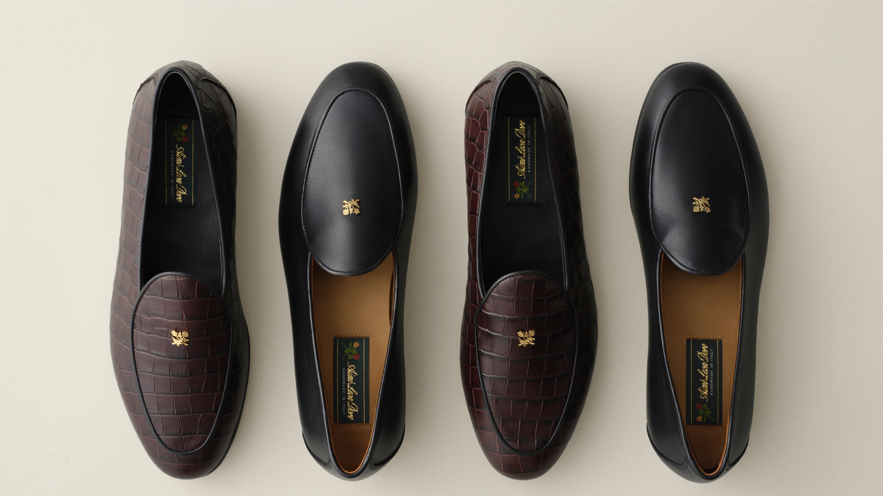 Four luxury loafers black leather and dark brown croc-embossed leather, with gold-tone logo hardware on the vamp and a tan interior lining.