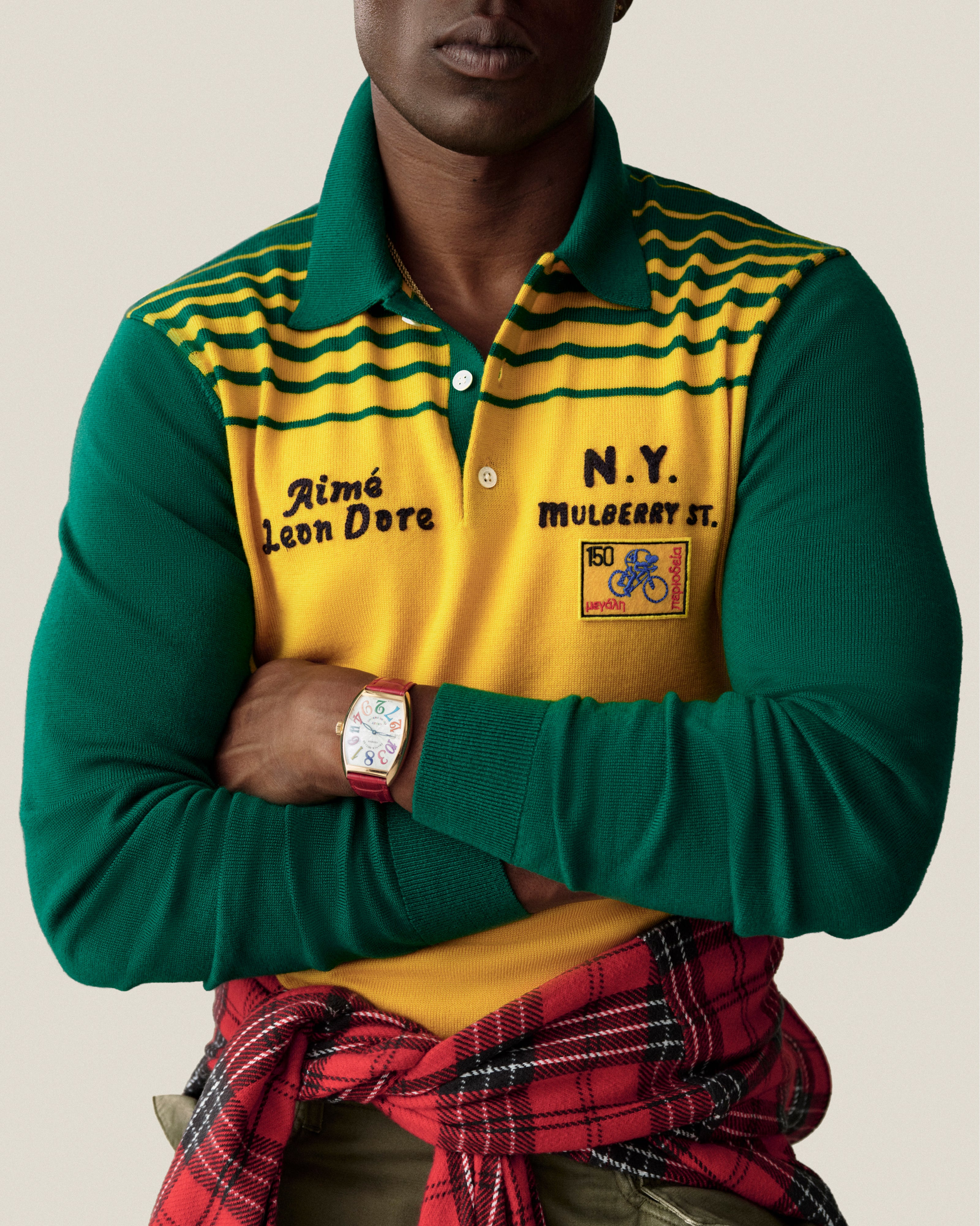 Man in green/yellow Merino Wool Knit Cycling Polo, arms crossed, red plaid shirt tied at waist.
