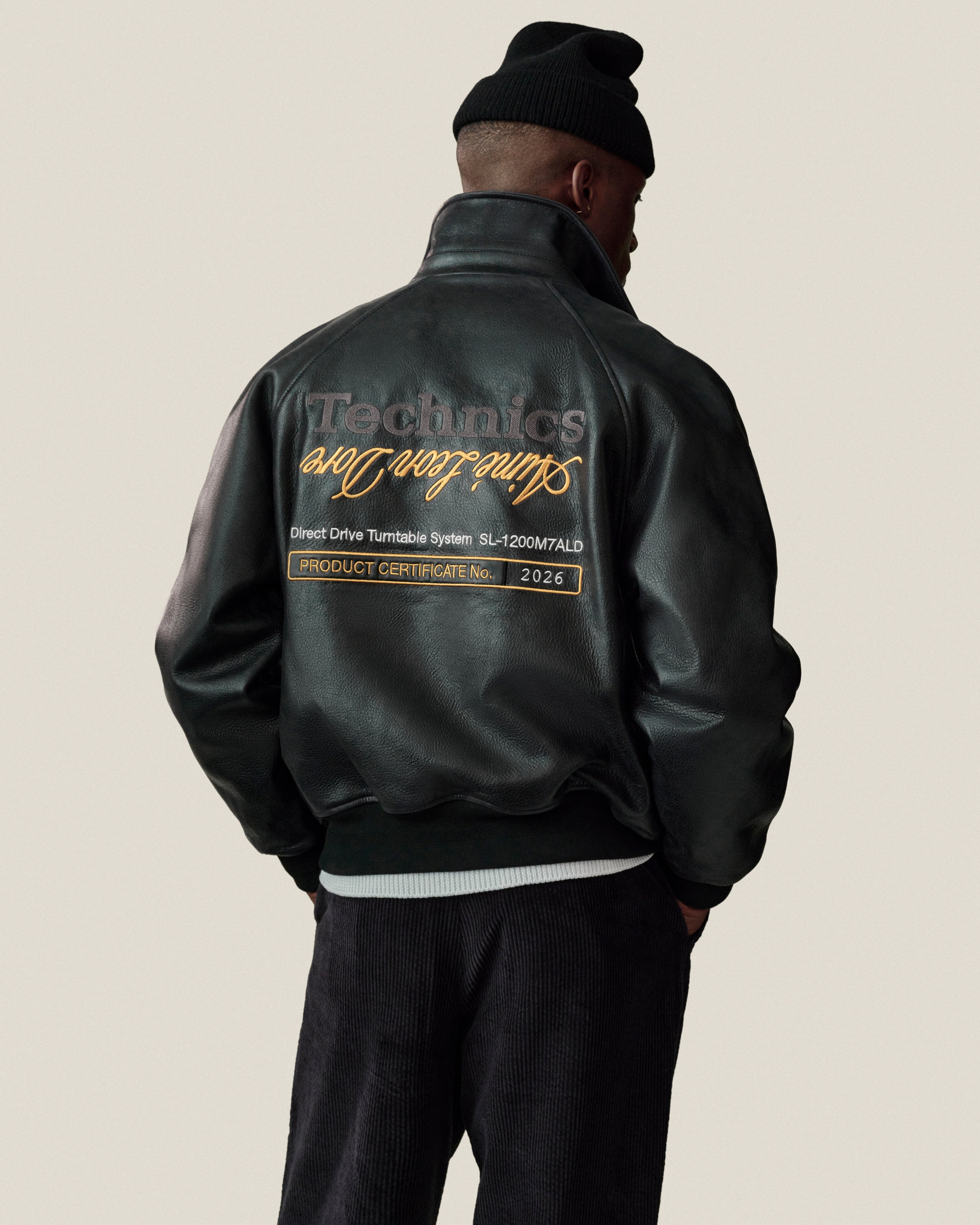 Man in ALD / Technics Varsity Leather Jacket and black beanie, text on back visible, facing away from camera.