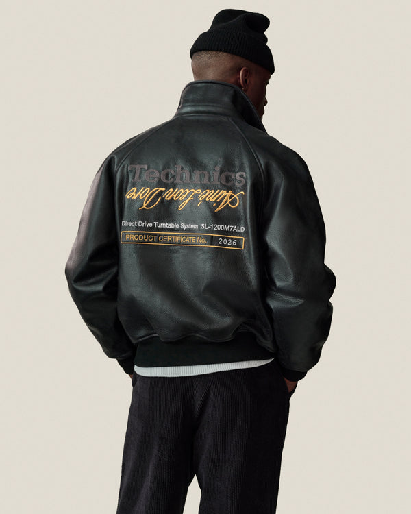 Man in ALD / Technics Varsity Leather Jacket and black beanie, text on back visible, facing away from camera.