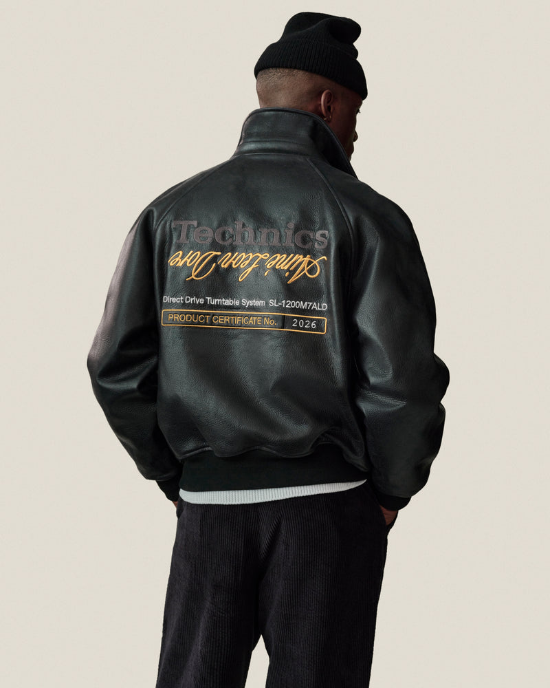 Man in ALD / Technics Varsity Leather Jacket and black beanie, text on back visible, facing away from camera.