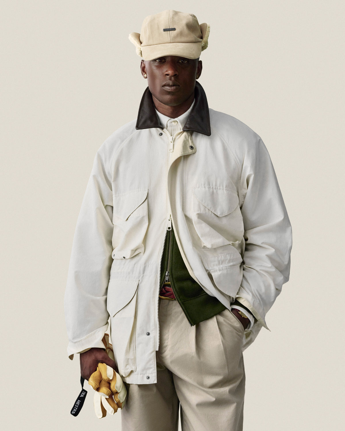 Man in Double Pleated Officer Pant and cap, holding yellow gloves, stands against a plain light background.