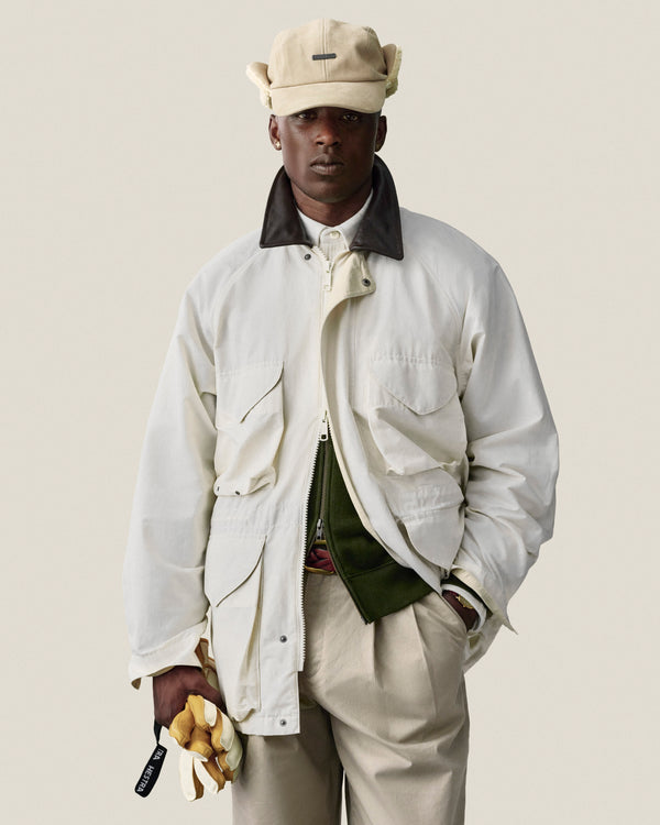 Man in Double Pleated Officer Pant and cap, holding yellow gloves, stands against a plain light background.