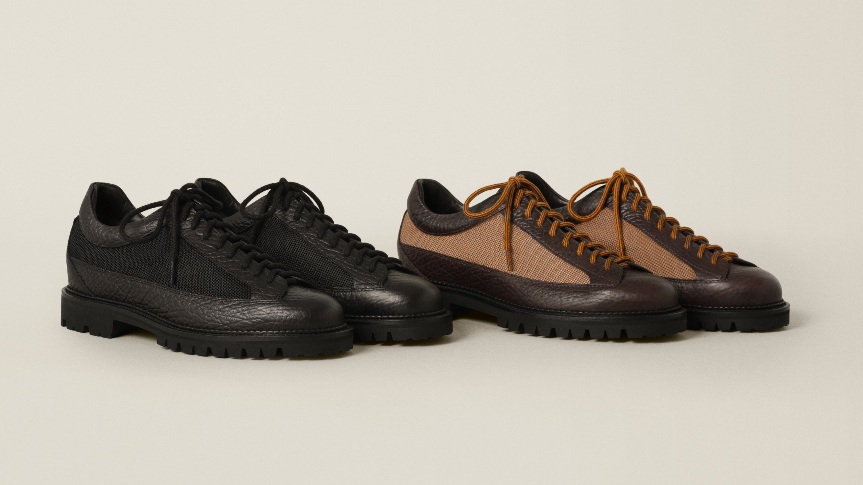 Two pairs of rugged lace-up shoes on a light beige studio background. The left pair is black leather with black laces and black soles.