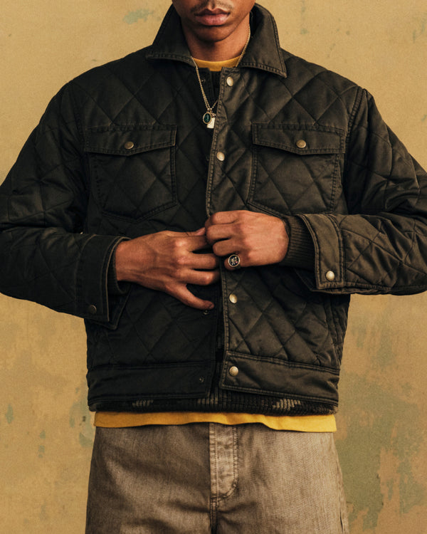 Person wearing a dark olive green Quilted Trucker Jacket with chest pockets and metal snap buttons.