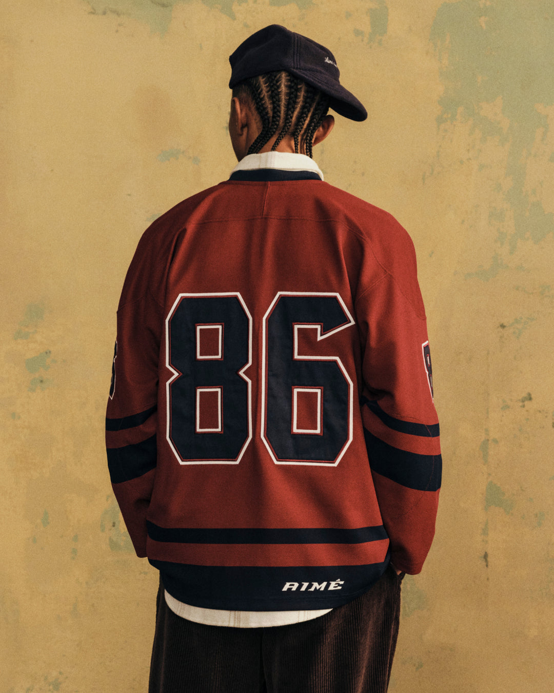 A person wearing a red Team Aimé Hockey Jersey with the number 86 on the back.