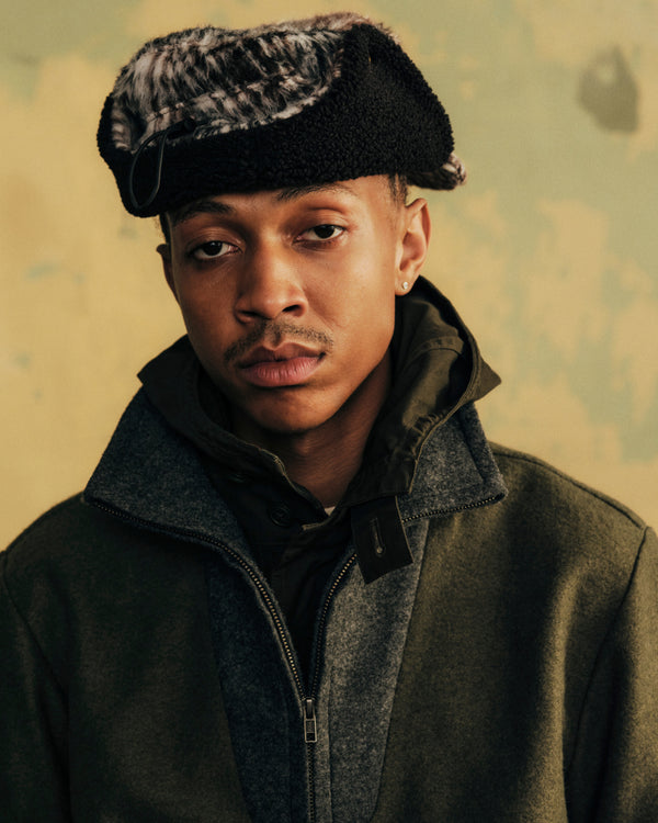 A person wearing a Plaid Wool Hunting Hat and an olive green coat.