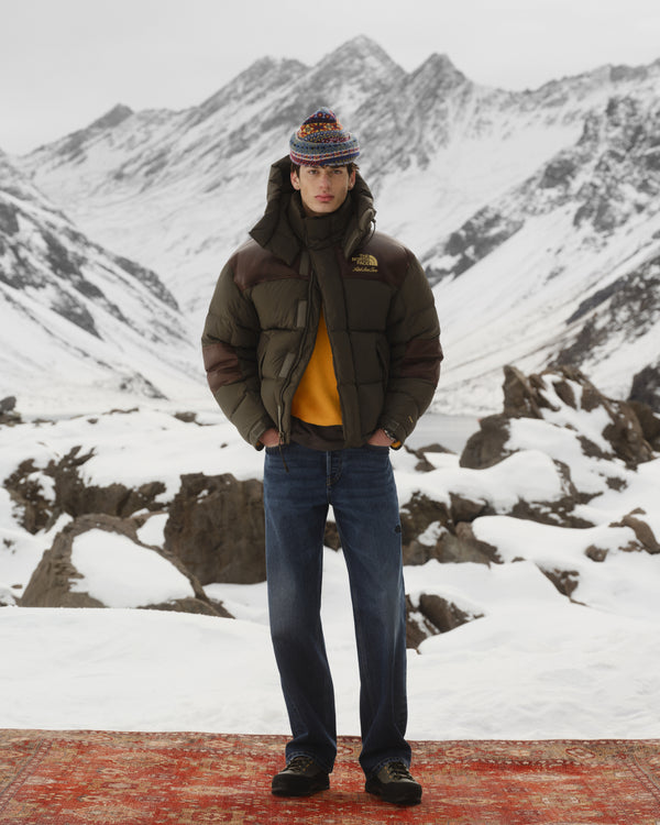 Someone in winter gear wears ALD/The North Face Verto Alpine GORE-TEX Hiking Shoes on a snowy mountain with rugged peaks.