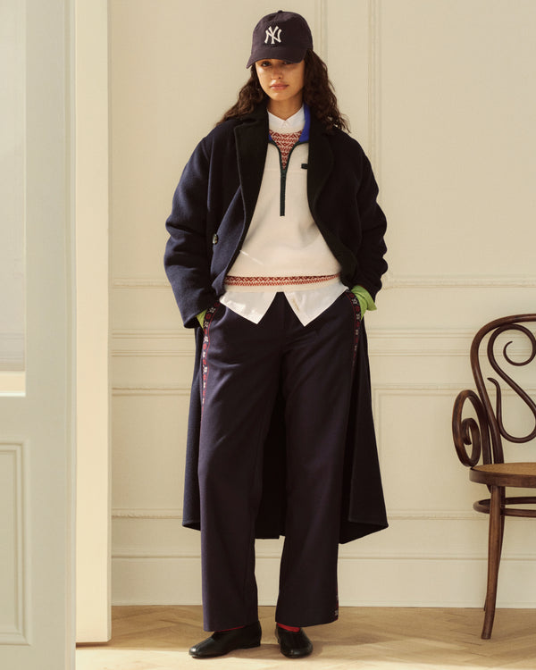 A person wears a Reversible Double Breasted Top Coat over a white quarter-zip, button-down, and dark trousers.