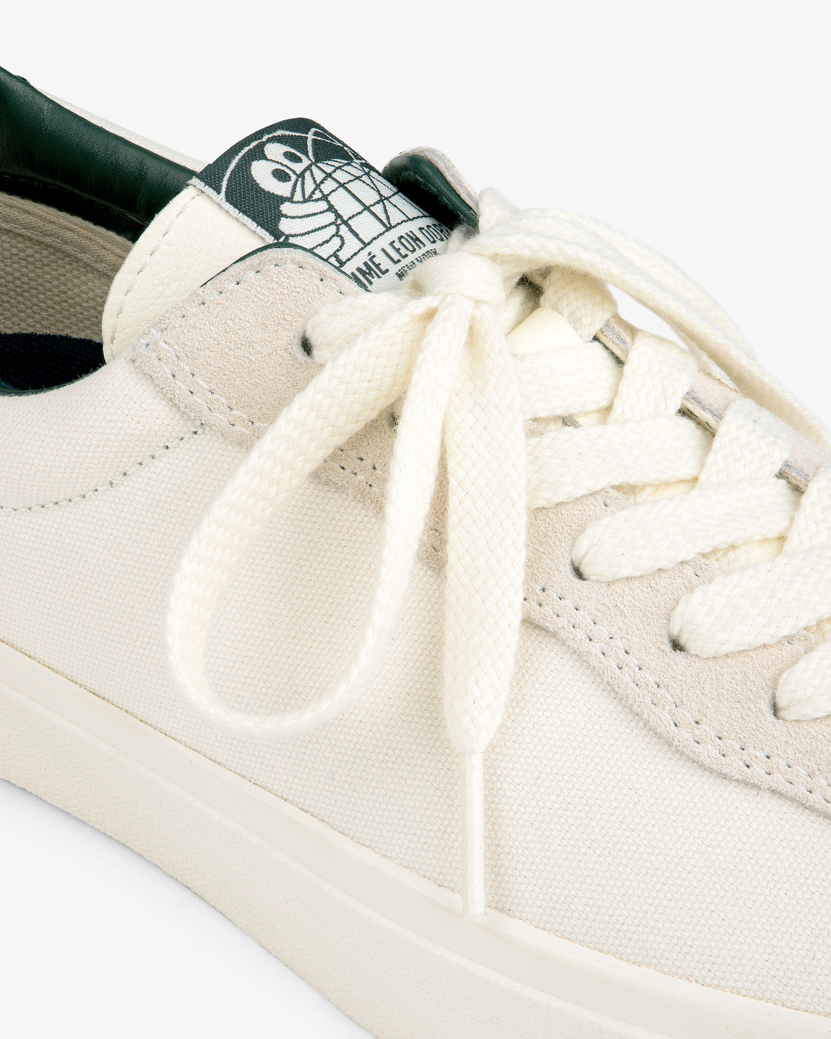 Close-up of the ALD / Last Resort AB VM001-LO Canvas sneaker with white laces and a green cartoon turtle tongue label.