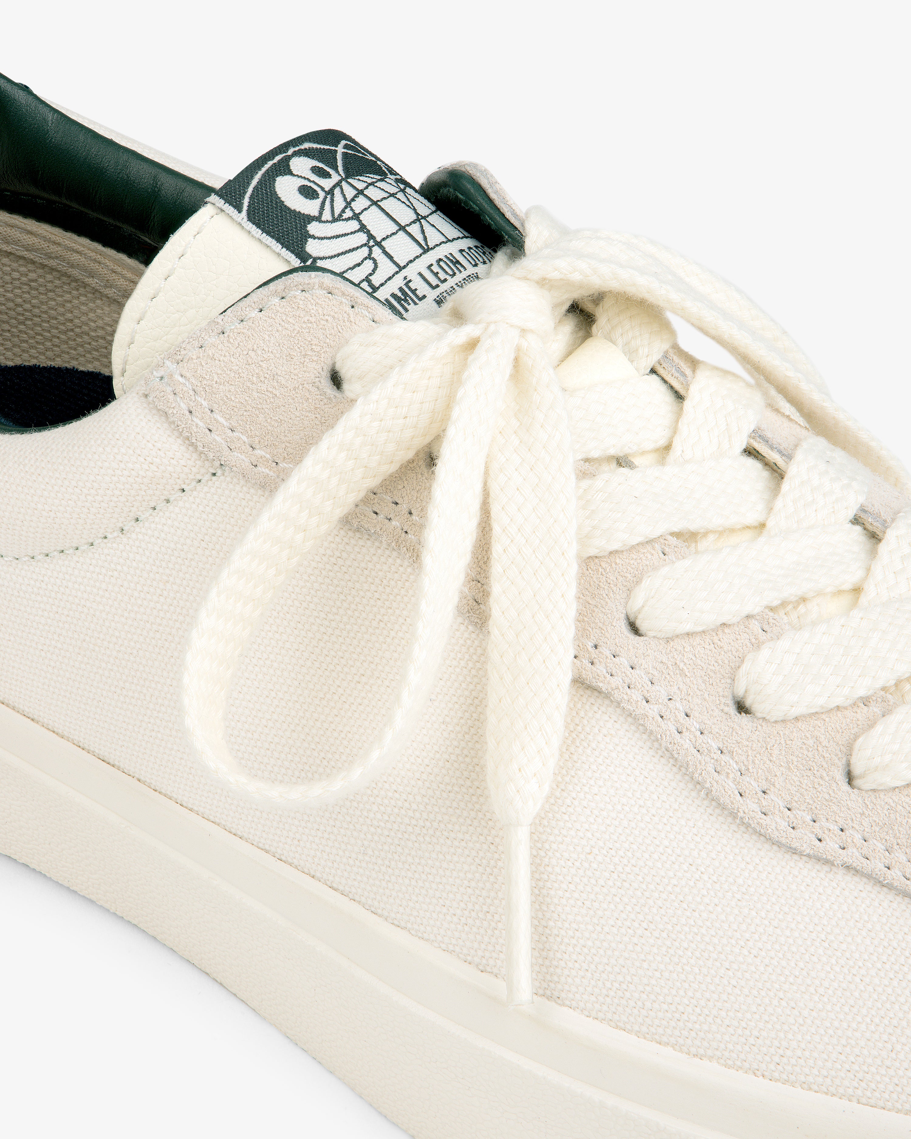 Close-up of the ALD / Last Resort AB VM001-LO Canvas sneaker with white laces and a green cartoon turtle tongue label.