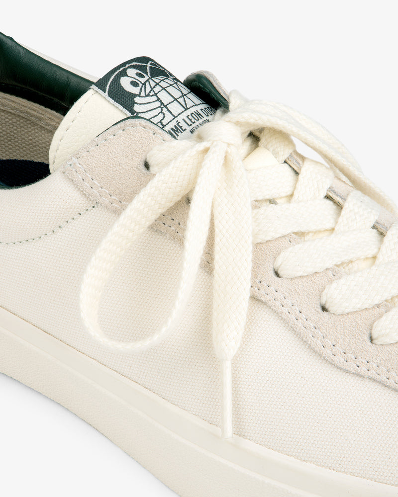 Close-up of the ALD / Last Resort AB VM001-LO Canvas sneaker with white laces and a green cartoon turtle tongue label.