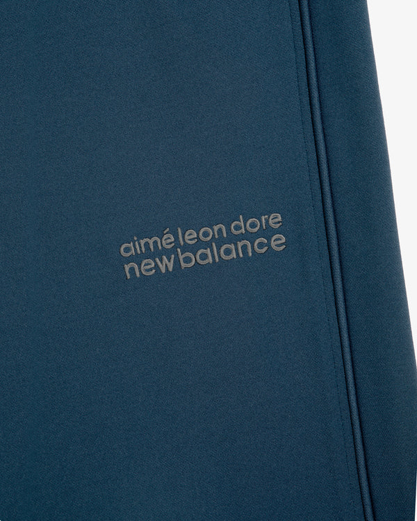 Close-up of blue ALD / New Balance RC56 Track Pant with embroidered gray logo.