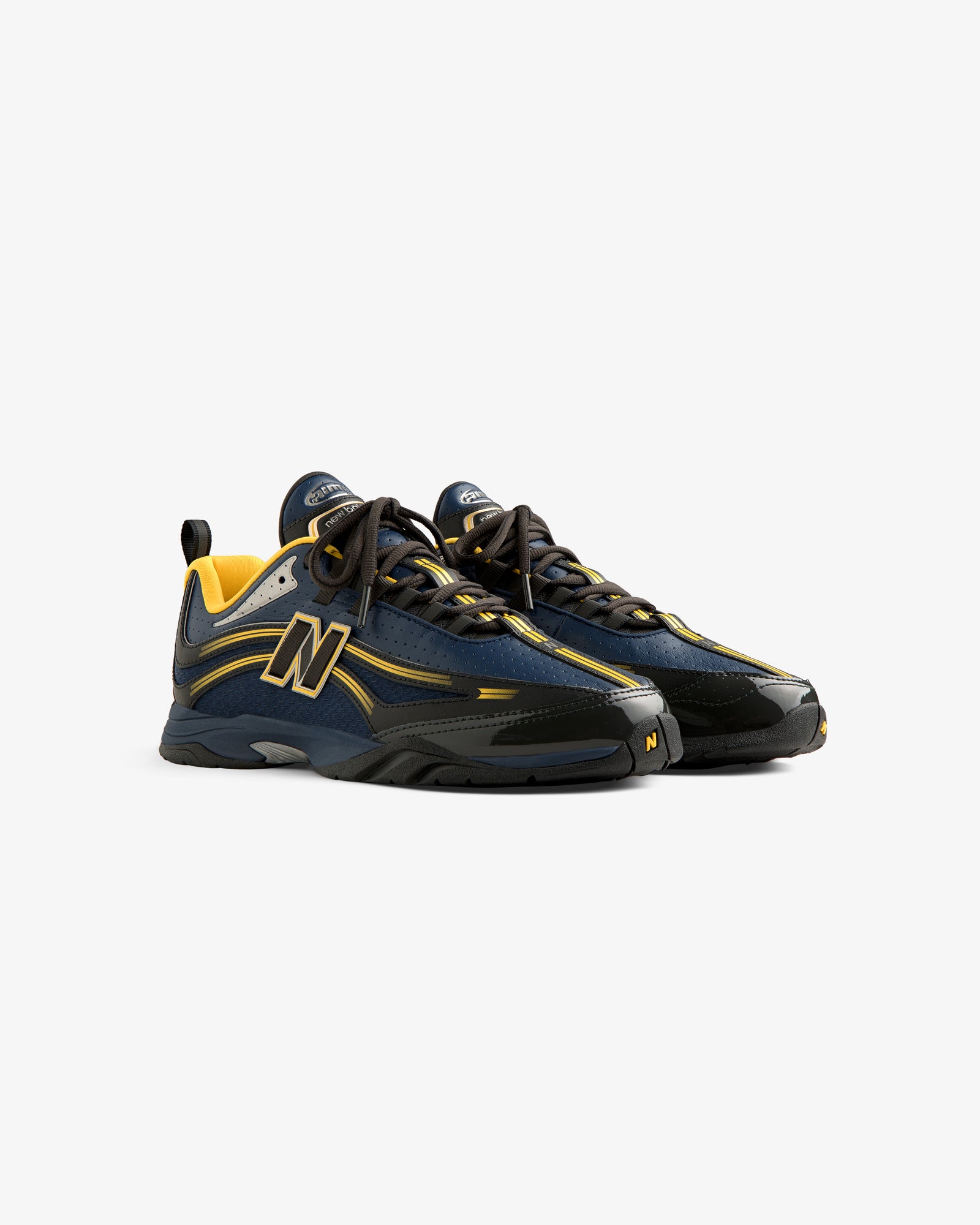 A pair of ALD / New Balance RC56 sneakers in navy blue, black, and yellow with black laces on a white background.